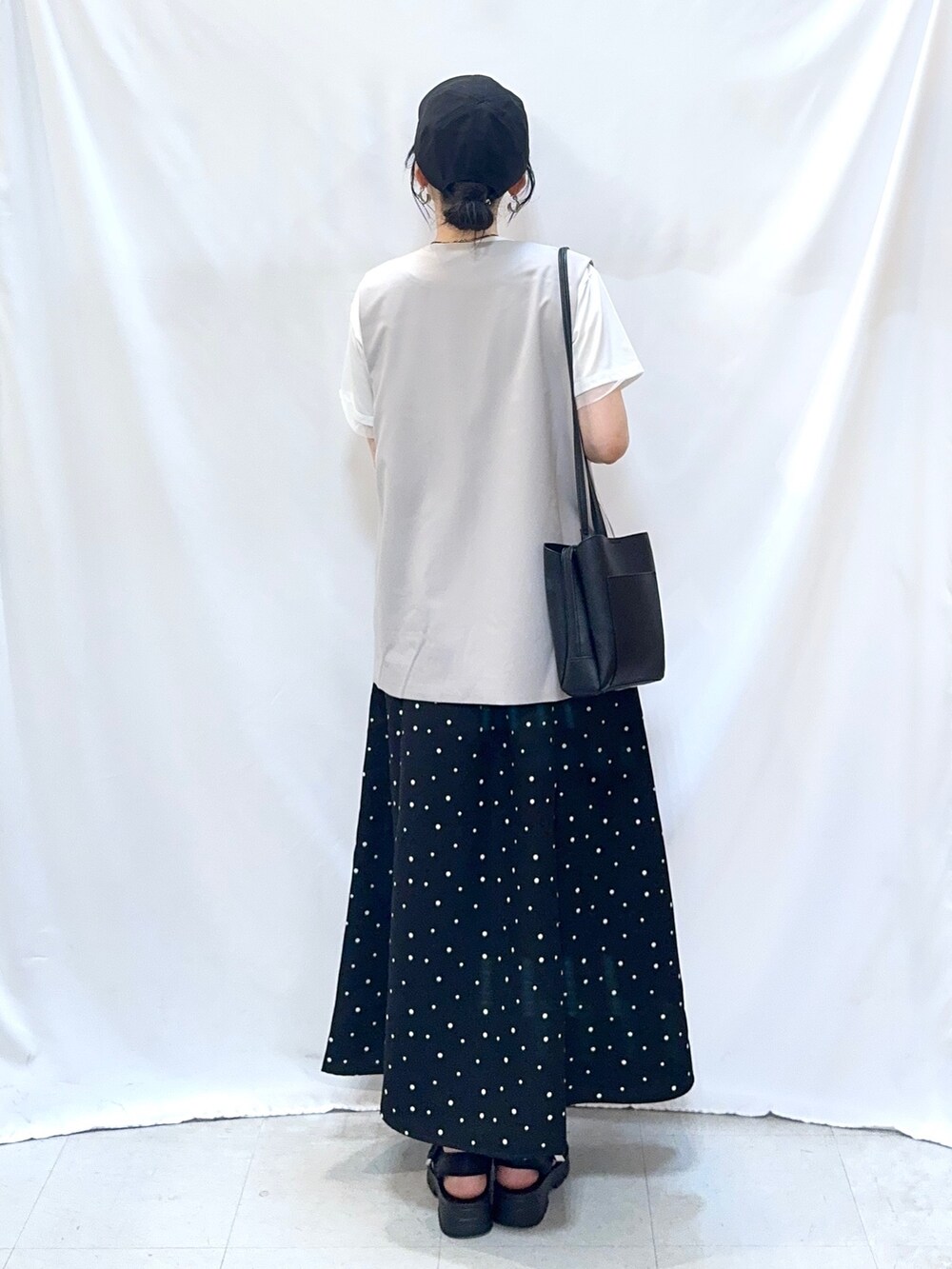 ベージュ系のベスト、ホワイト系のTシャツ/カットソー、ブラック系のスカートを着用したレディースの夏コーディネートの5枚目の写真