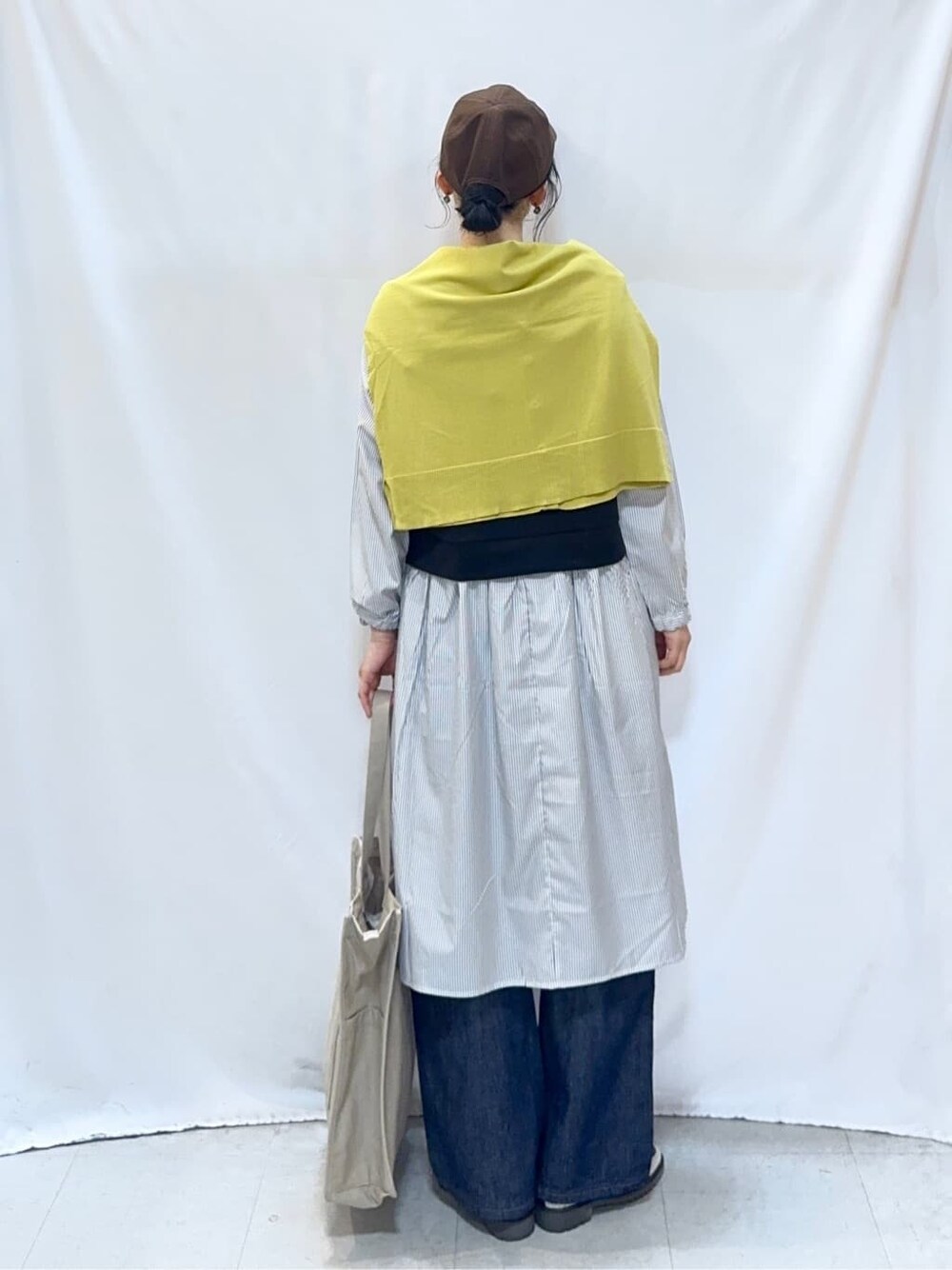 イエロー系のカーディガン/ボレロ、ブラック系のワンピース、ブルー系のデニムパンツを着用したレディースの春コーディネートの5枚目の写真