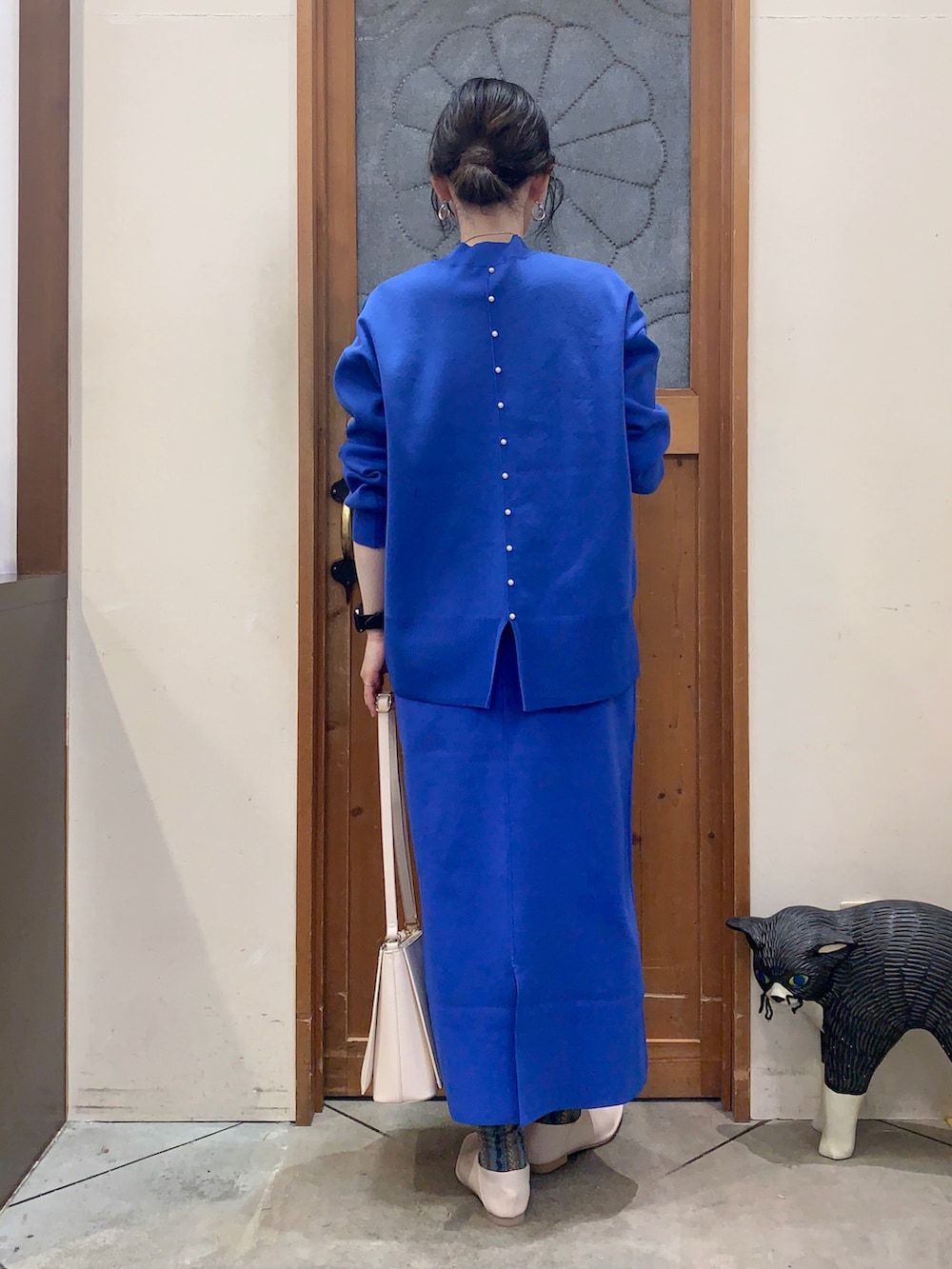 ブルー系のニット/セーター、ブルー系のスカート、ホワイト系のパンプスを着用したレディースの冬コーディネートの4枚目の写真