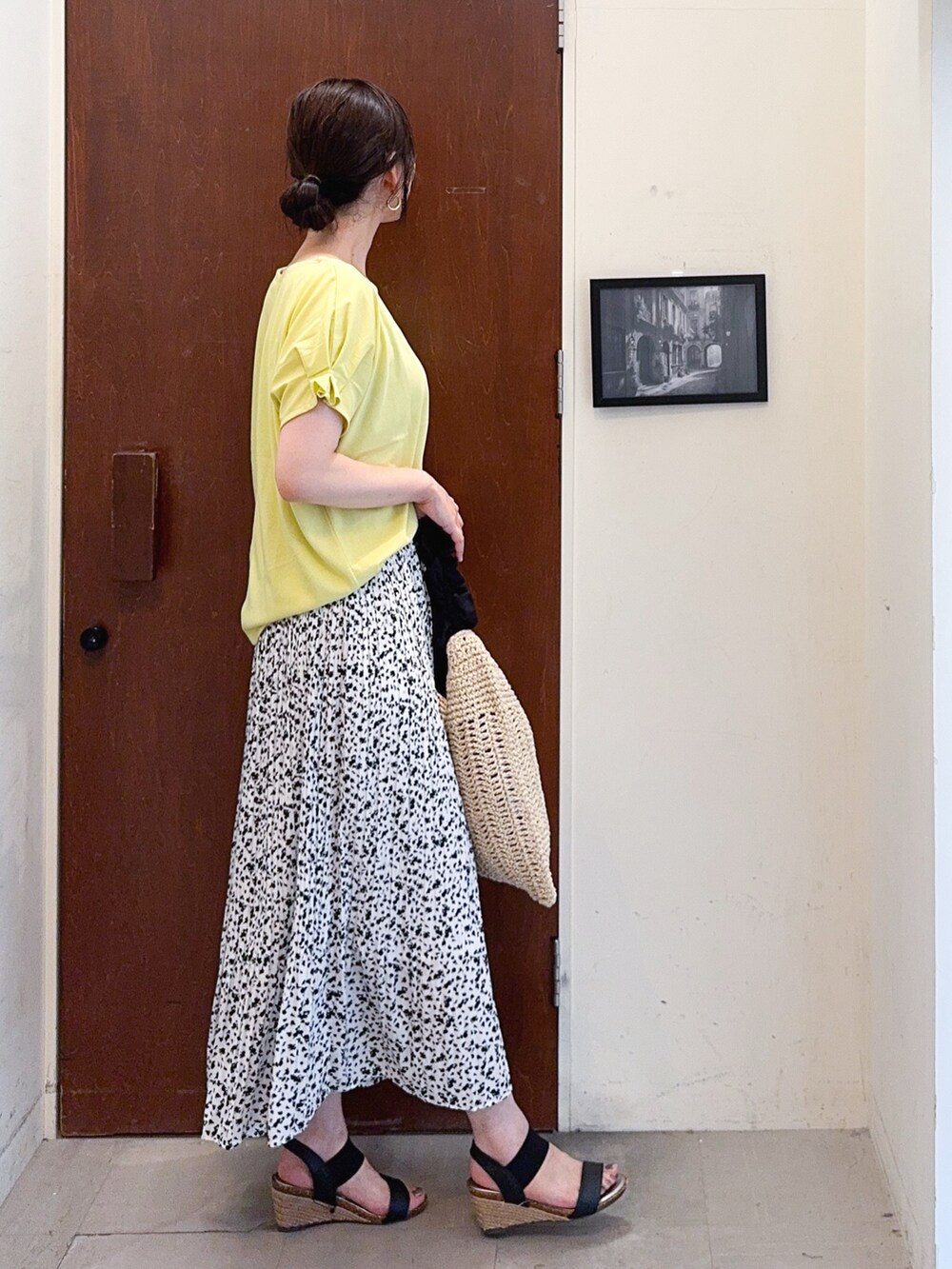 イエロー系のTシャツ/カットソー、ホワイト系のスカート、ブラック系のトートバッグを着用したレディースの夏コーディネートの3枚目の写真