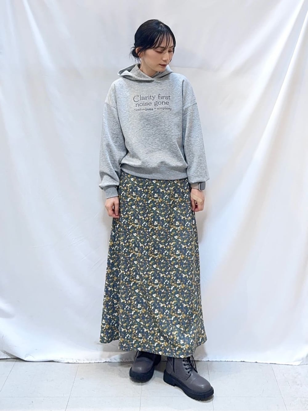 グレー系のパーカー、ブルー系のスカート、ブラウン系のブーツを着用したレディースの冬コーディネートの2枚目の写真