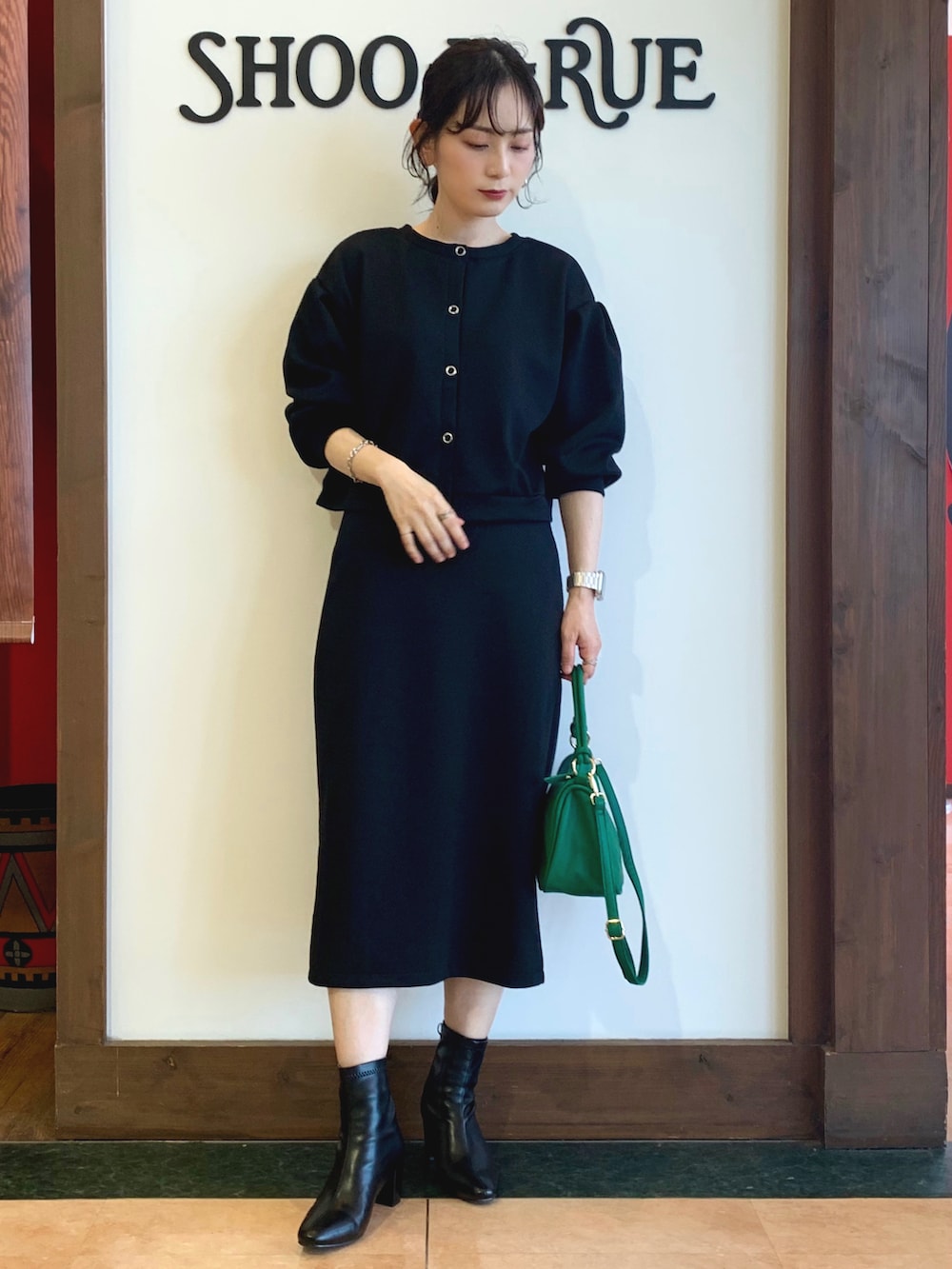 ブラック系のカーディガン/ボレロ、ブラック系のスカート、グリーン系のショルダーバッグを着用したレディースの秋コーディネートの2枚目の写真