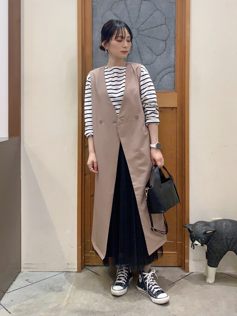 ブラック系のTシャツ/カットソー、ベージュ系のベスト、ブラック系のスカートを着用したレディースの春コーディネートの2枚目の写真