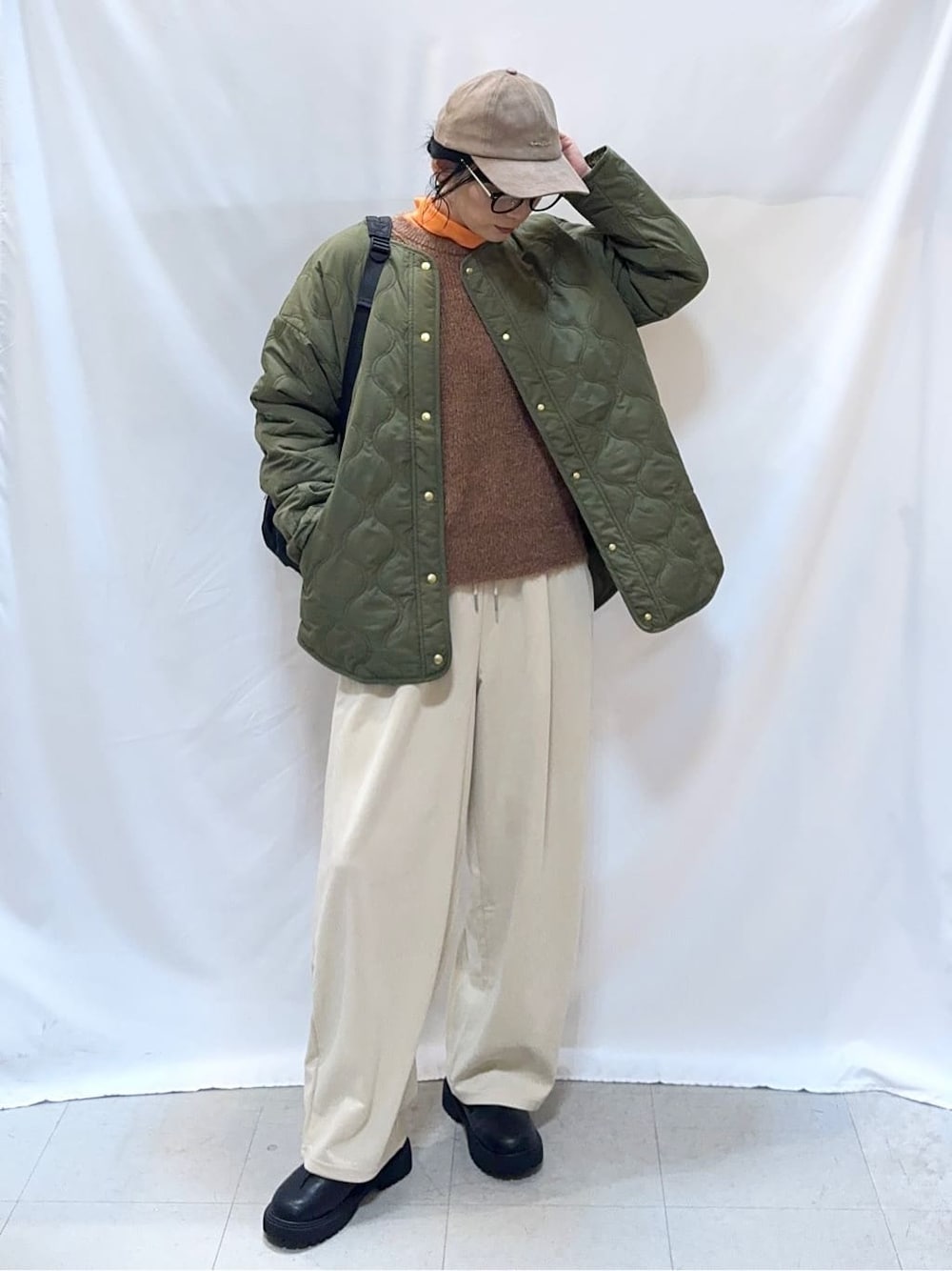 グリーン系のブルゾン、ブラウン系のニット/セーター、オレンジ系のTシャツ/カットソーを着用したレディースの秋コーディネートの3枚目の写真