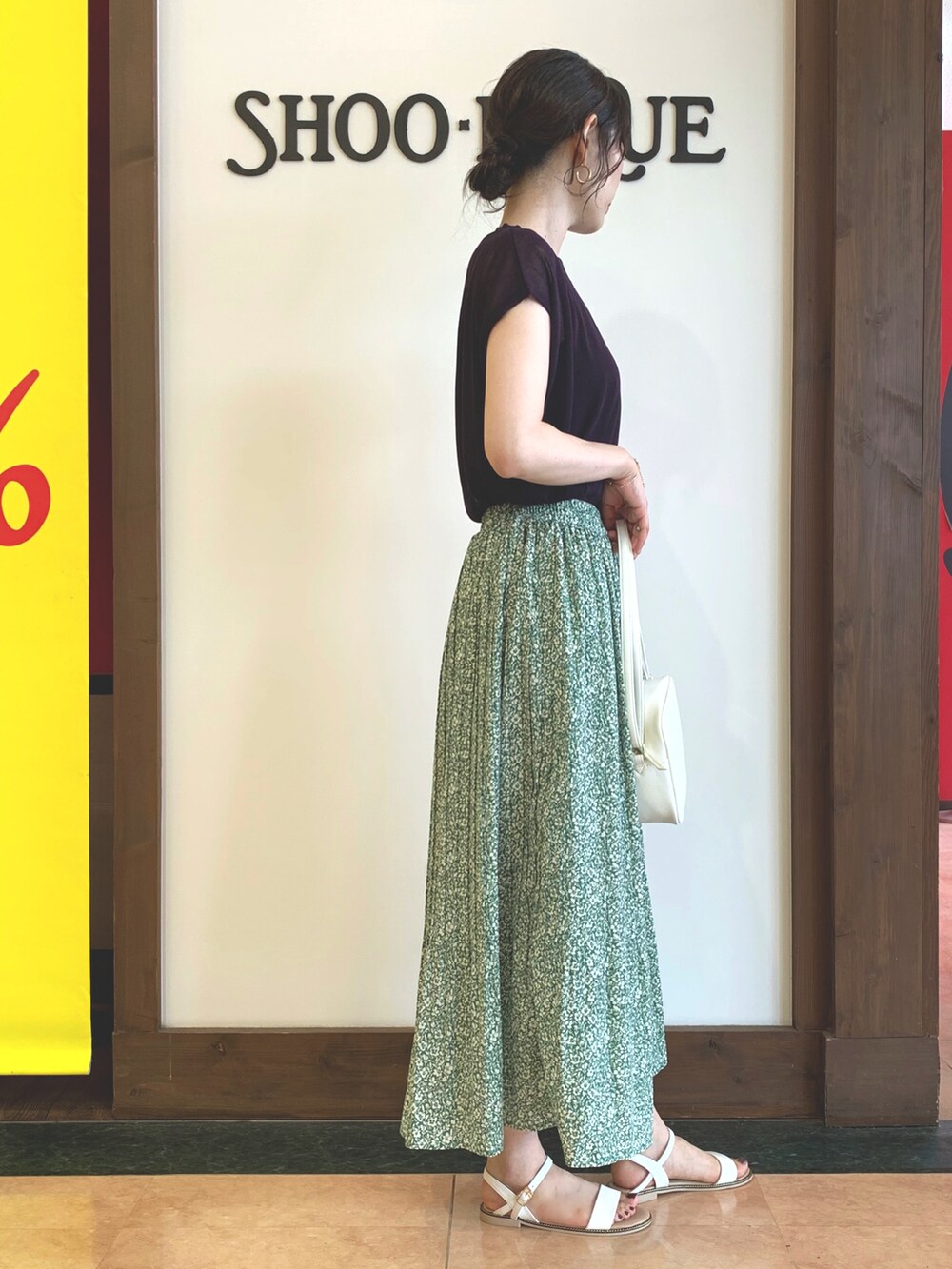 ブルー系のニット/セーター、グリーン系のスカート、ホワイト系のショルダーバッグを着用したレディースの夏コーディネートの2枚目の写真