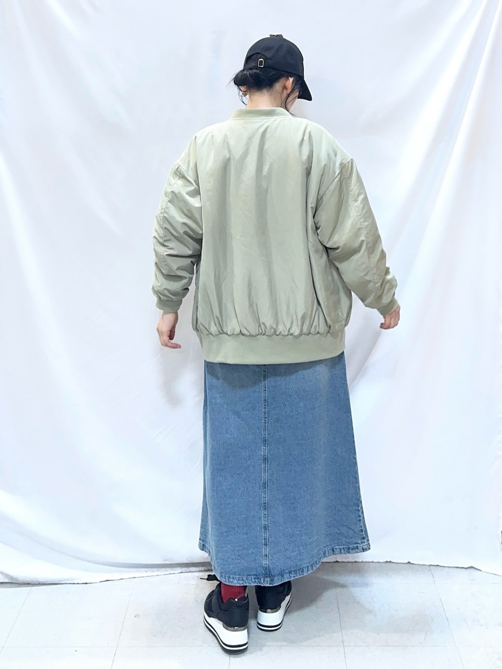 グリーン系のブルゾン、ピンク系のニット/セーター、ブルー系のデニムスカートを着用したレディースの冬コーディネートの4枚目の写真