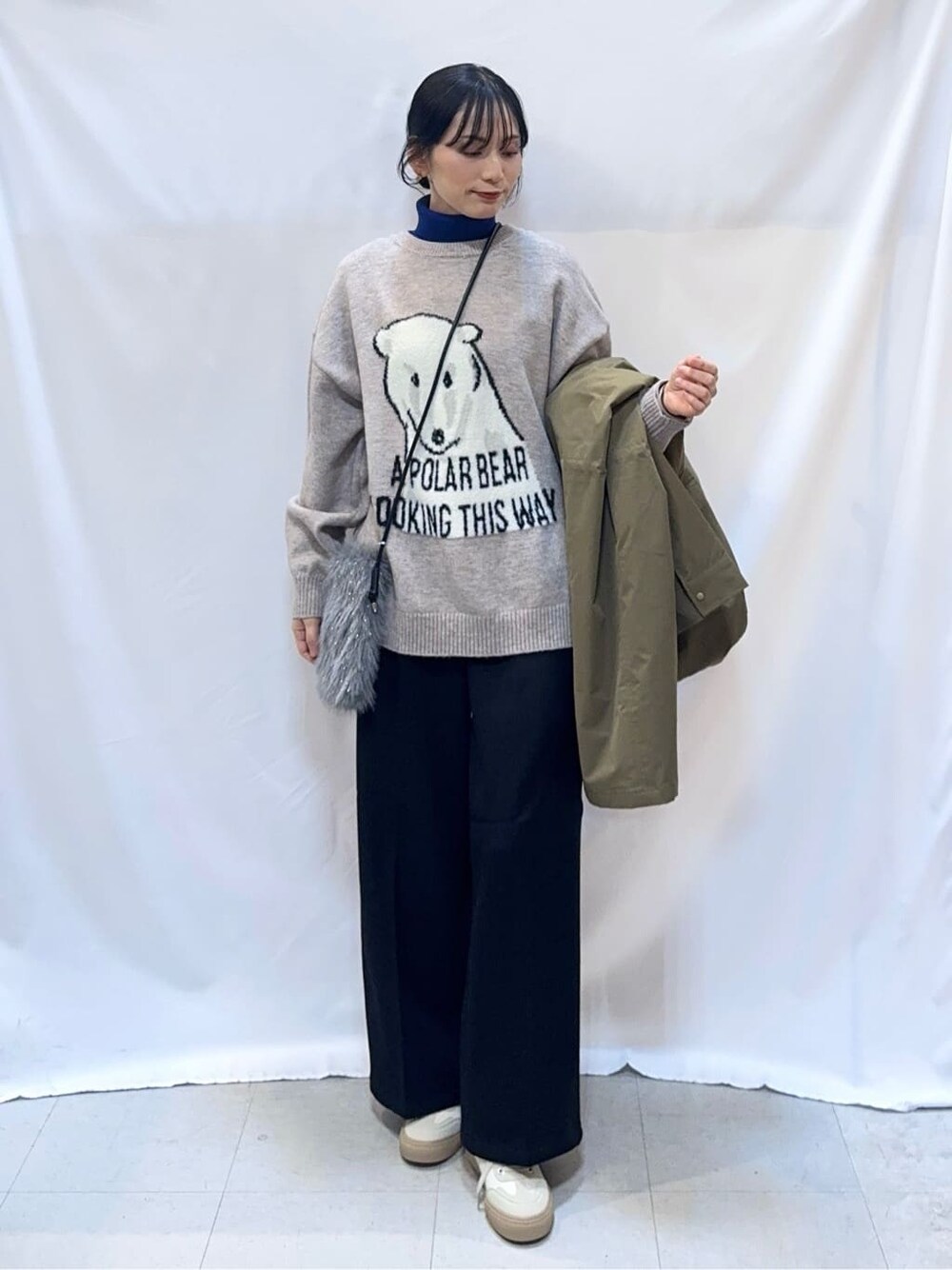 グリーン系のミリタリージャケット、グレー系のニット/セーター、ブルー系のニット/セーターを着用したレディースの冬コーディネートの4枚目の写真