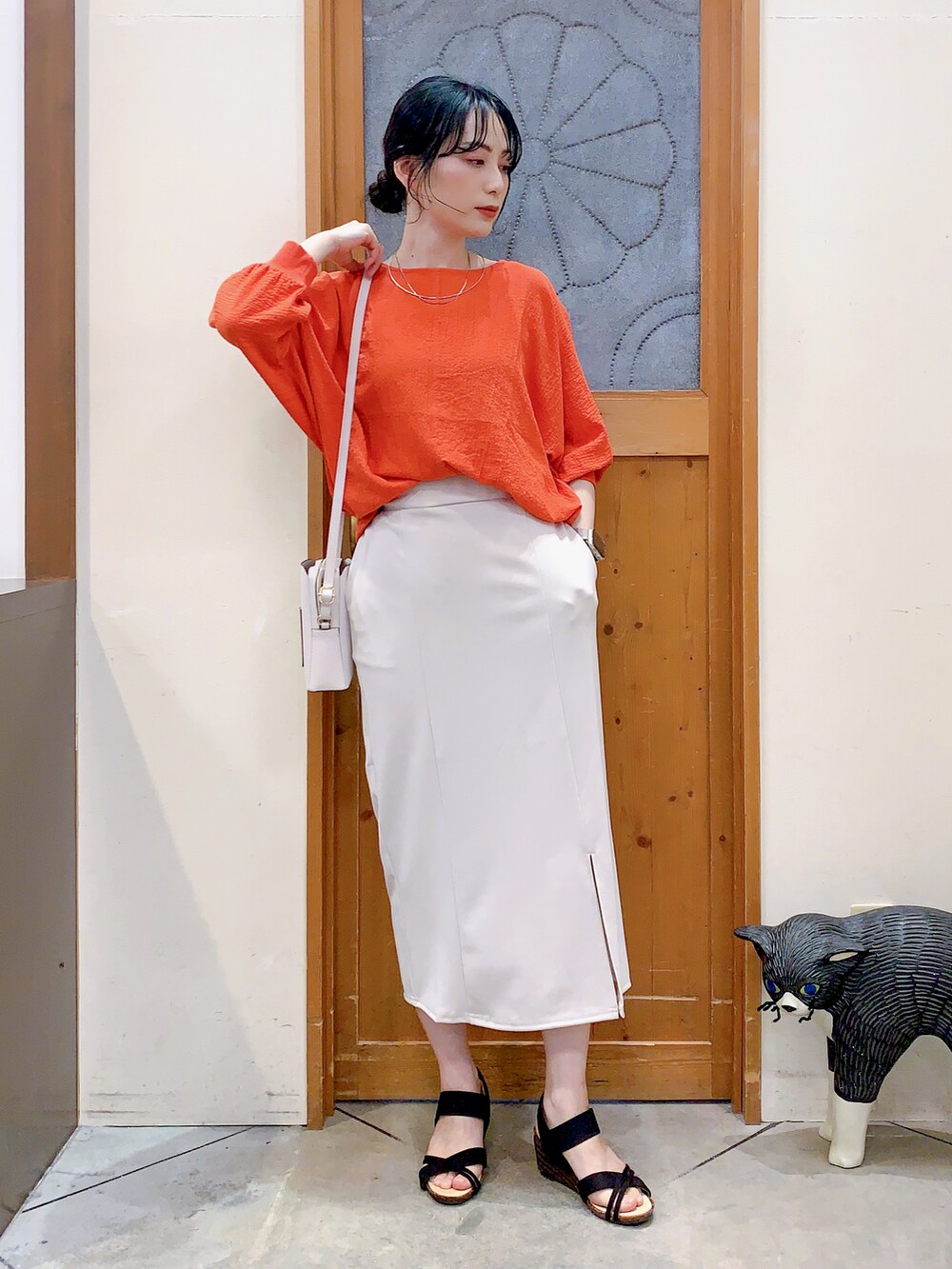 オレンジ系のシャツ/ブラウス、ホワイト系のスカート、ホワイト系のショルダーバッグを着用したレディースの春コーディネートの2枚目の写真