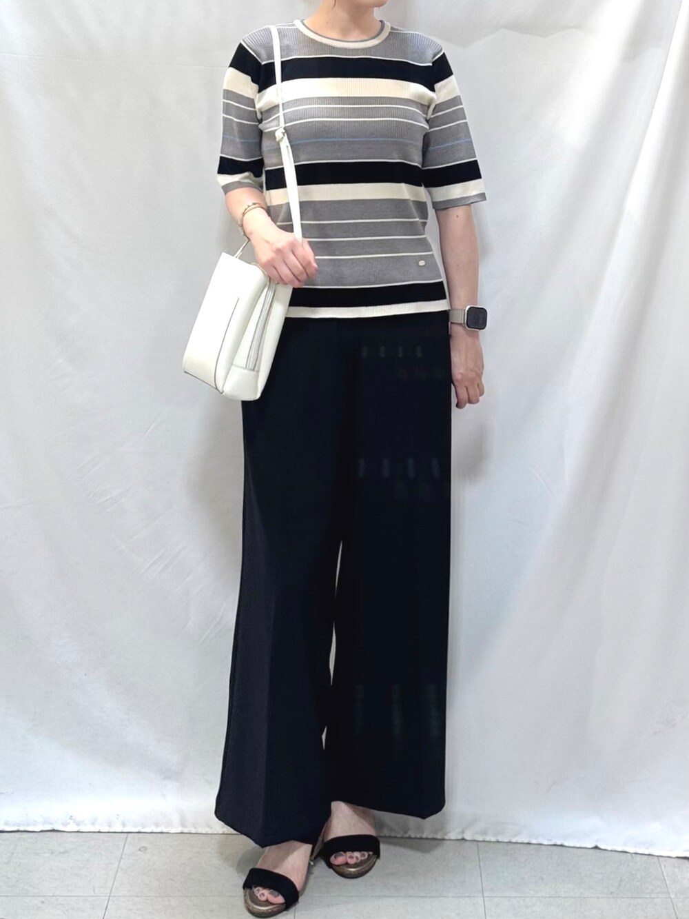 グレー系のニット/セーター、ブラック系のその他パンツ、ブラック系のサンダルを着用したレディースの夏コーディネートの5枚目の写真