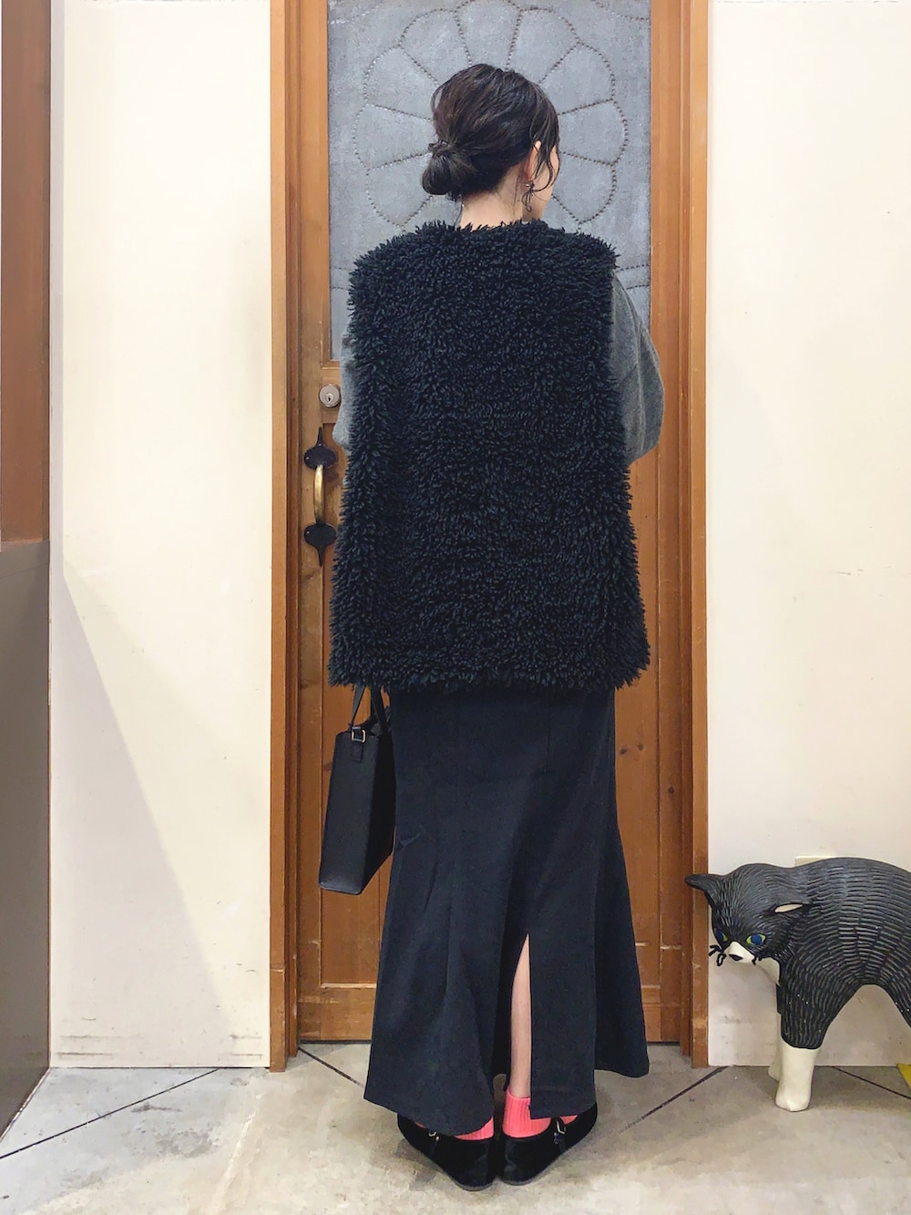 グレー系のニット/セーター、ブラック系のスカート、ブラック系のベストを着用したレディースの冬コーディネートの3枚目の写真