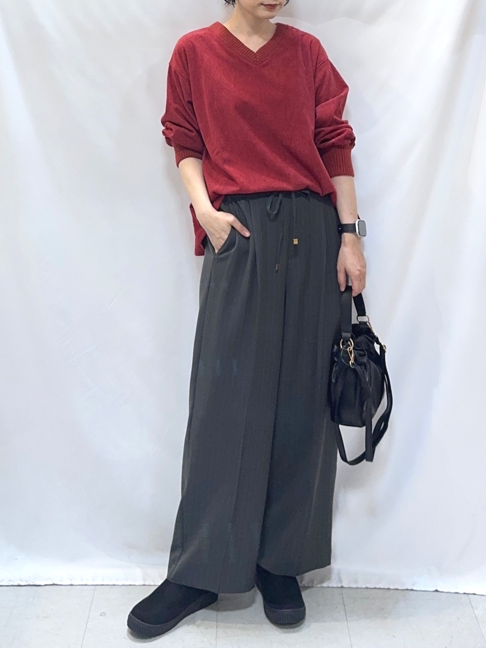 レッド系のTシャツ/カットソー、グレー系のその他パンツ、ブラック系のブーツを着用したレディースの秋コーディネートの5枚目の写真