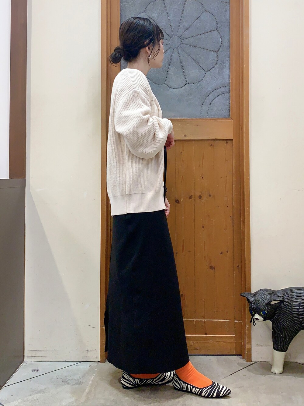 ベージュ系のTシャツ/カットソー、ホワイト系のカーディガン/ボレロ、ブラック系のスカートを着用したレディースの冬コーディネートの2枚目の写真