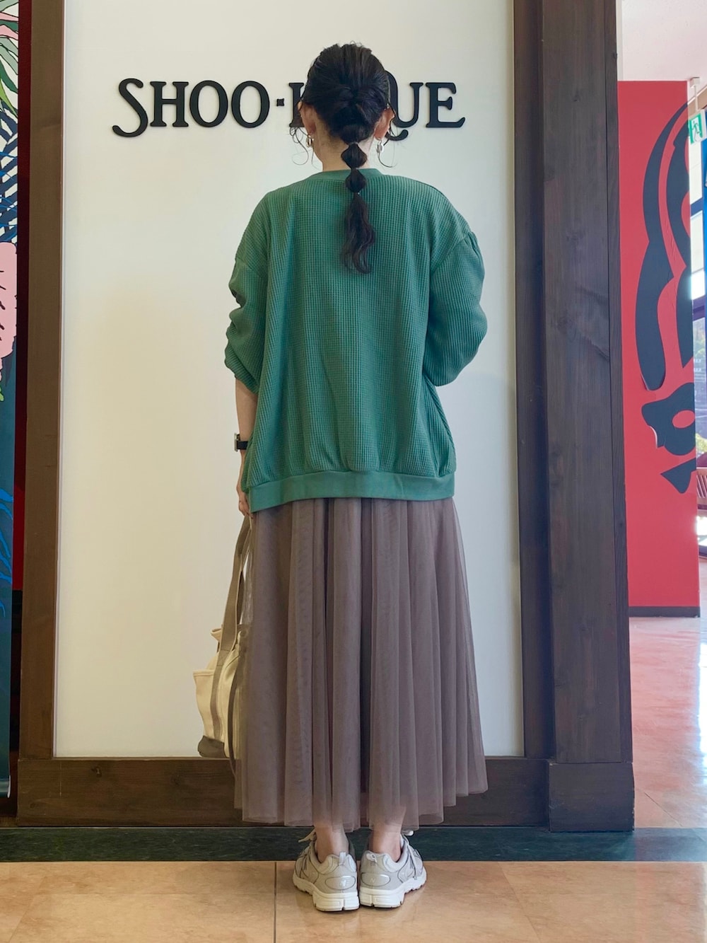 グリーン系のTシャツ/カットソー、グリーン系のカーディガン/ボレロ、ベージュ系のスカートを着用したレディースの春コーディネートの3枚目の写真