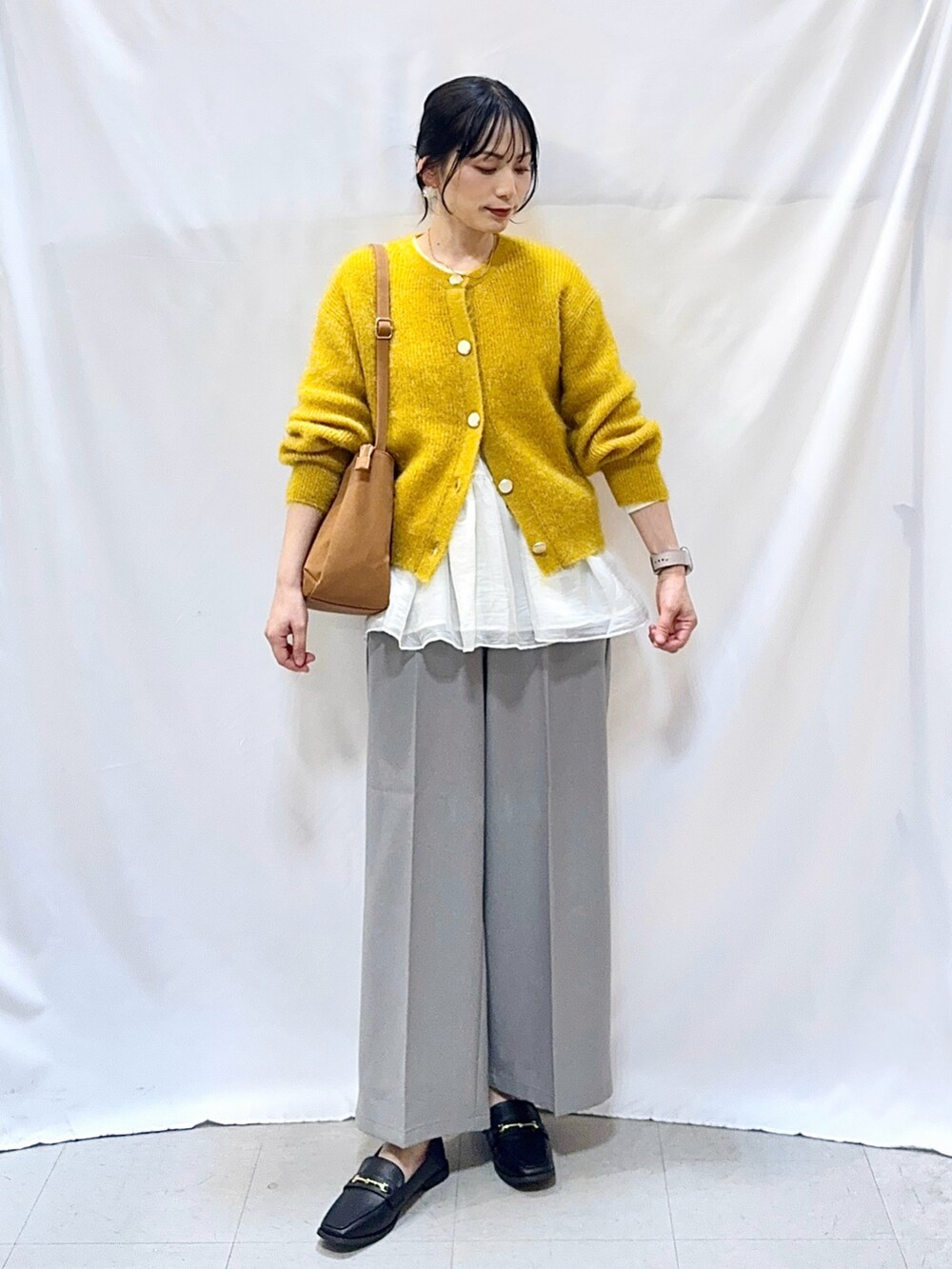 イエロー系のカーディガン/ボレロ、ホワイト系のTシャツ/カットソー、グレー系のその他パンツを着用したレディースの秋コーディネートの2枚目の写真