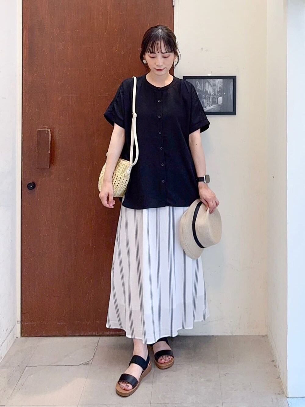 ブラック系のシャツ/ブラウス、ホワイト系のスカート、ブラック系のサンダルを着用したレディースの夏コーディネートの2枚目の写真