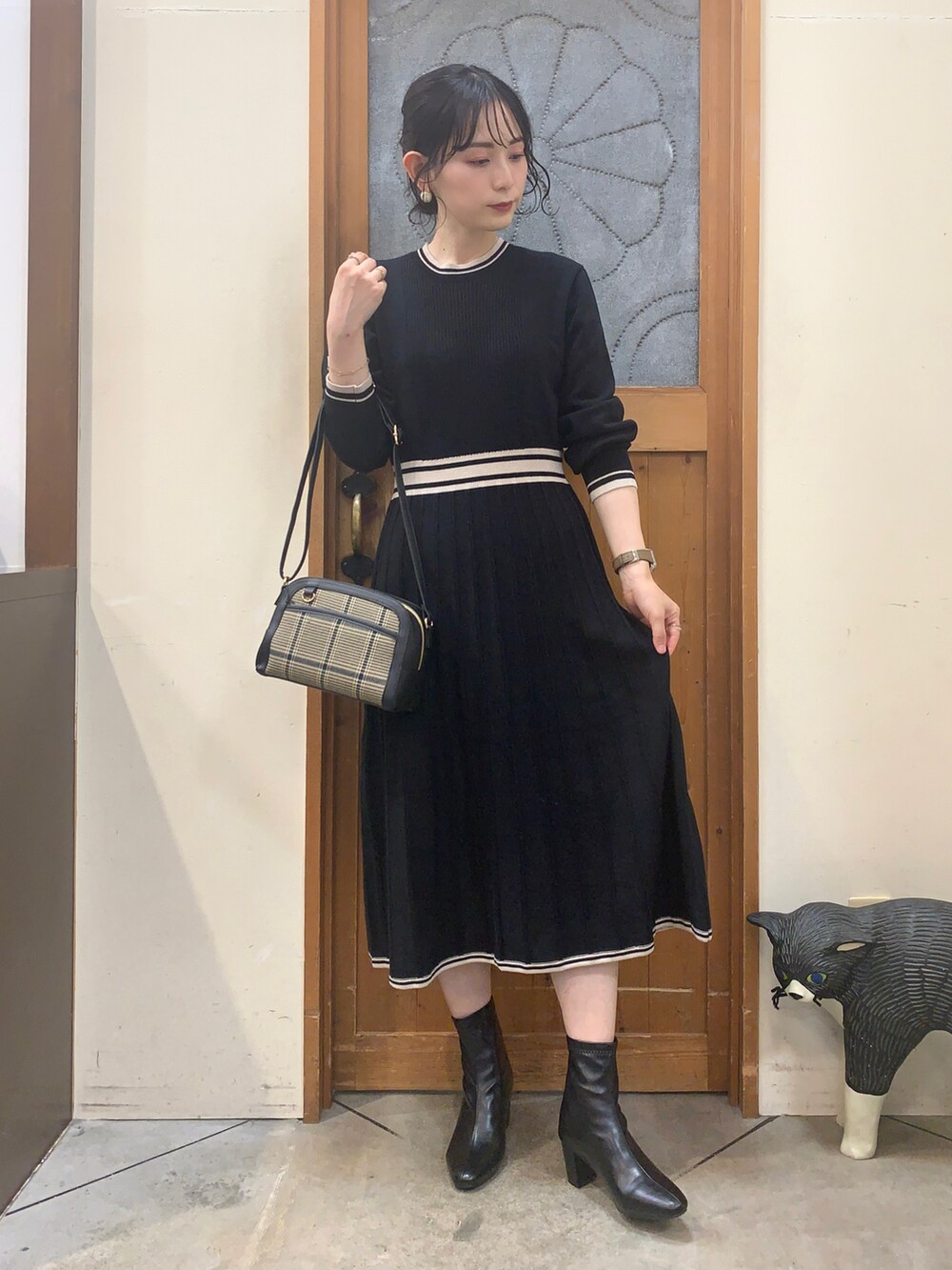 ブラック系のワンピース、ブラック系のブーツ、グリーン系のショルダーバッグを着用したレディースの秋コーディネートの2枚目の写真