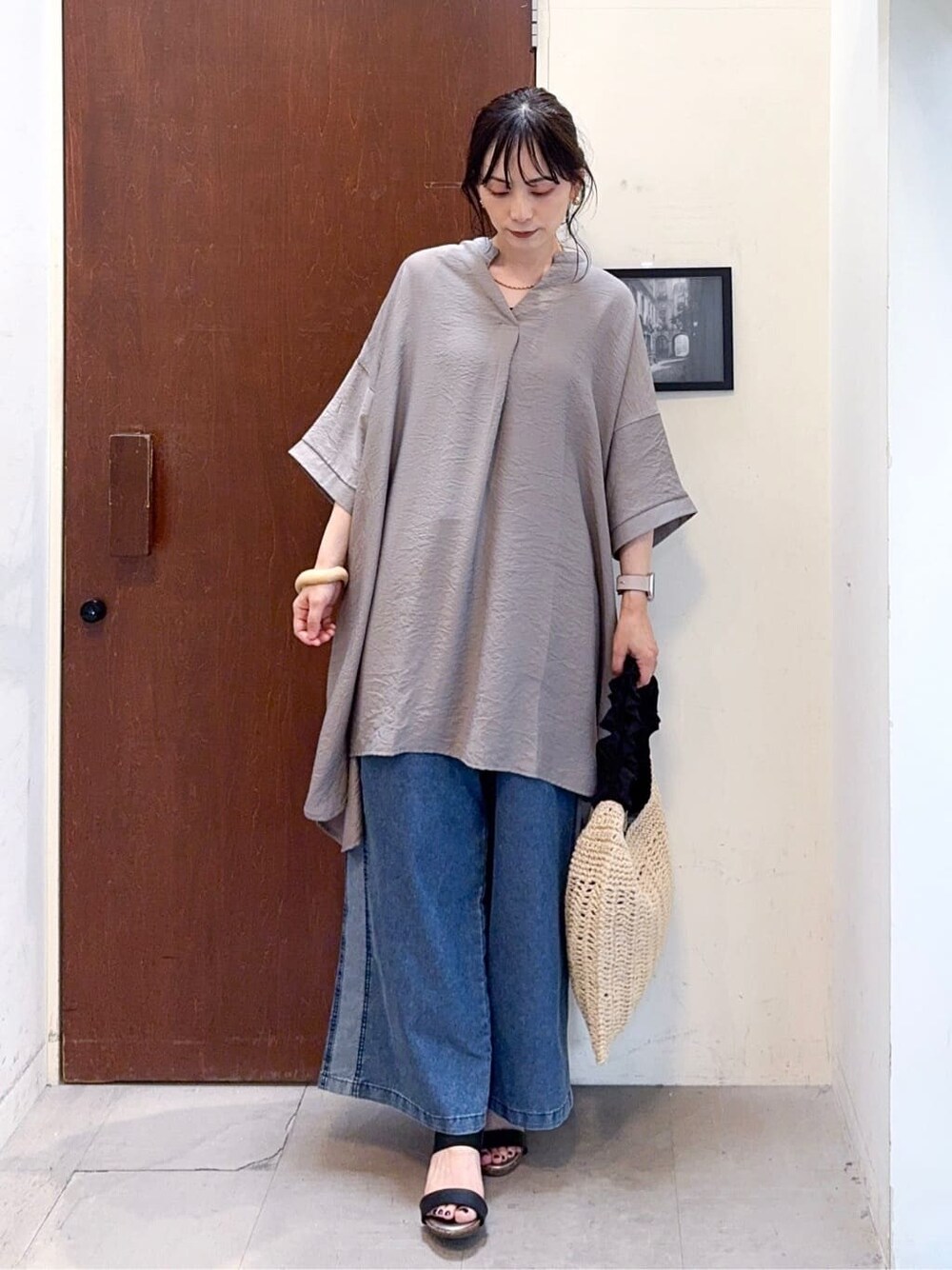 ブラウン系のチュニック、ブルー系のデニムパンツ、ブラック系のサンダルを着用したレディースの夏コーディネートの2枚目の写真