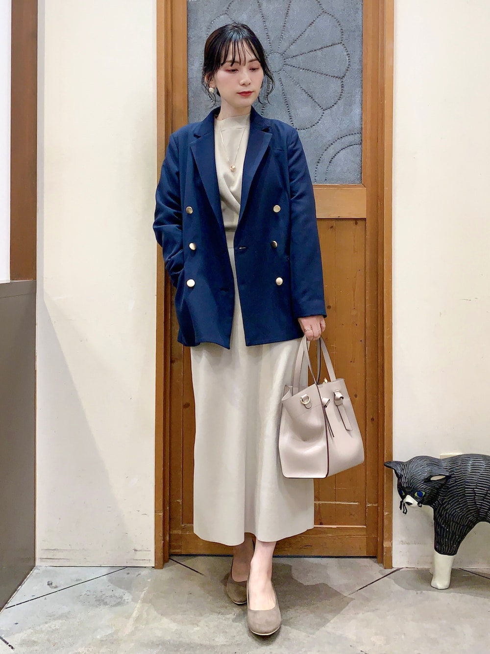 ブルー系のテーラードジャケット、ベージュ系のニット/セーター、ベージュ系のスカートを着用したレディースの春コーディネートの2枚目の写真