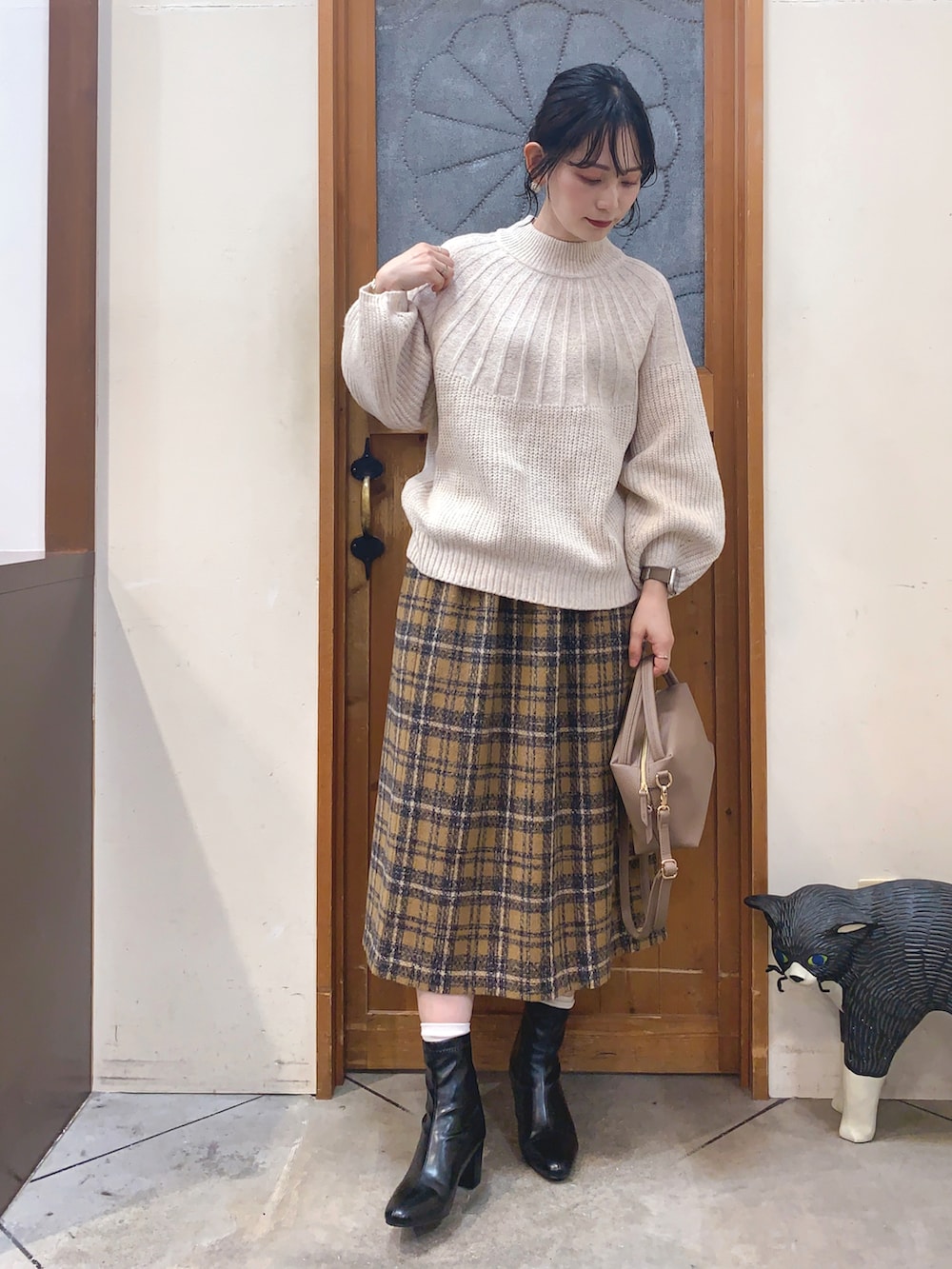 ベージュ系のニット/セーター、イエロー系のスカート、グレー系のショルダーバッグを着用したレディースの冬コーディネートの2枚目の写真