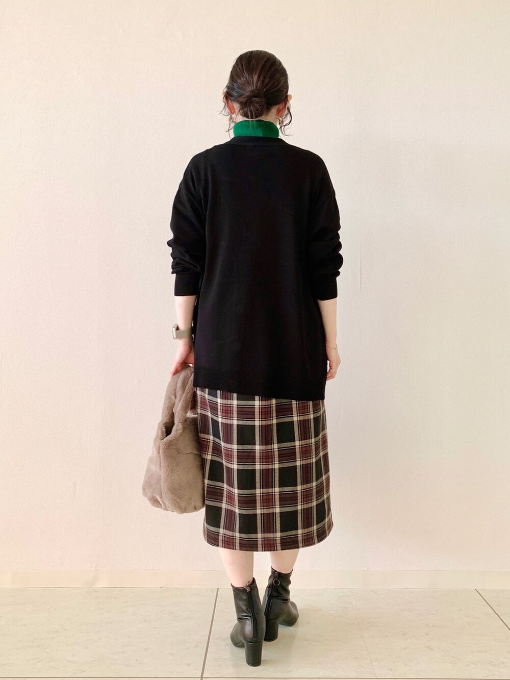 グリーン系のニット/セーター、ブラック系のカーディガン/ボレロ、ブラック系のスカートを着用したレディースの秋コーディネートの3枚目の写真