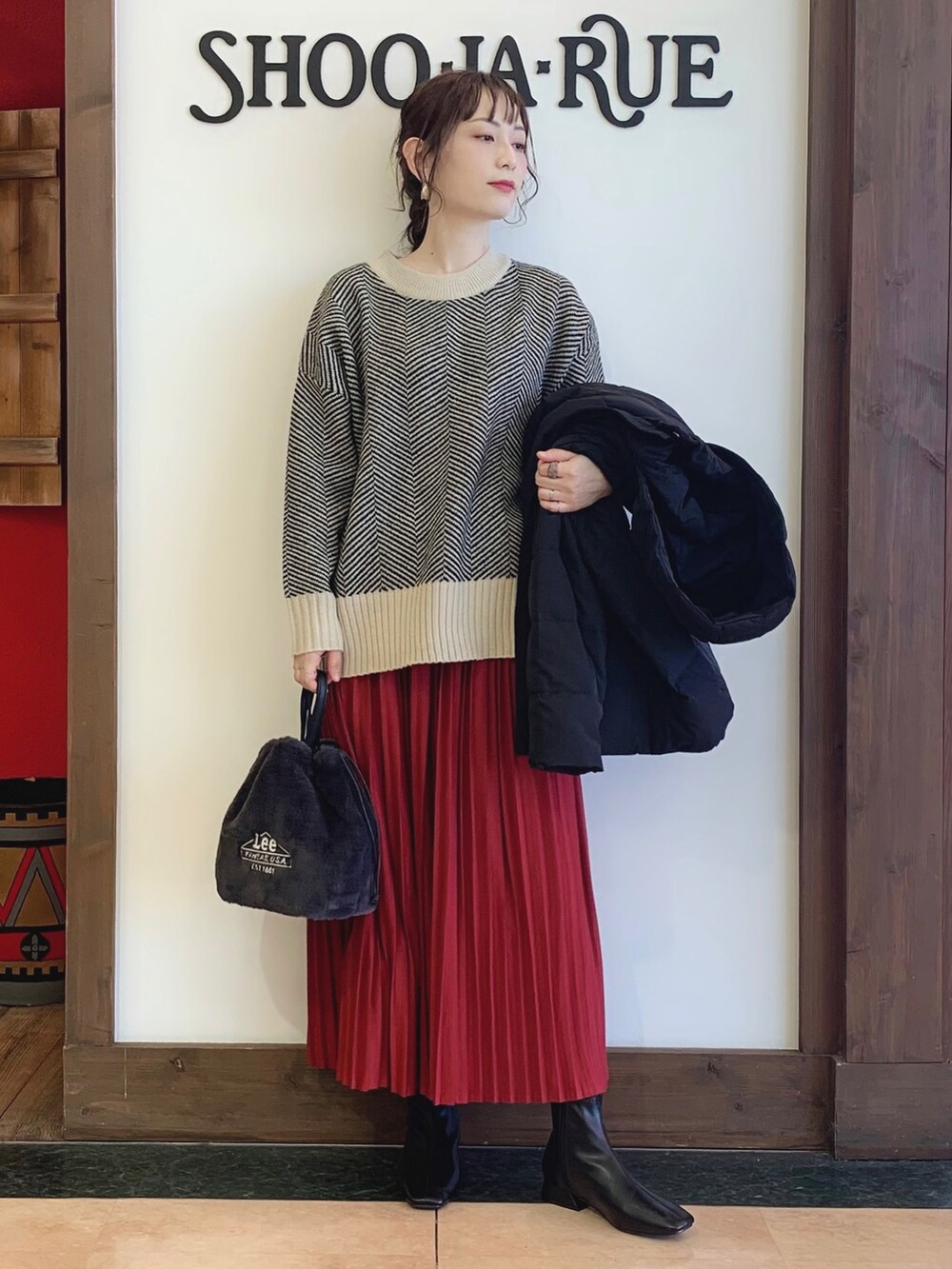 ベージュ系のニット/セーター、ブラック系のダウンジャケット/コート、レッド系のその他パンツを着用したレディースの秋コーディネートの2枚目の写真