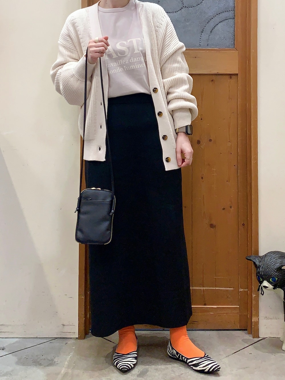 ベージュ系のTシャツ/カットソー、ホワイト系のカーディガン/ボレロ、ブラック系のスカートを着用したレディースの冬コーディネートの3枚目の写真