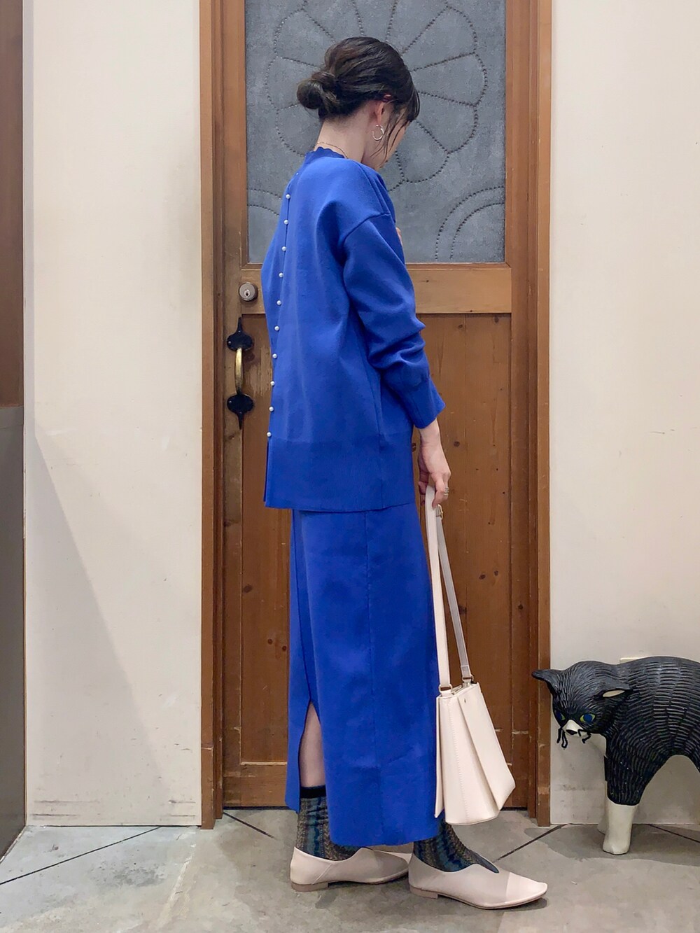 ブルー系のニット/セーター、ブルー系のスカート、ホワイト系のパンプスを着用したレディースの冬コーディネートの3枚目の写真
