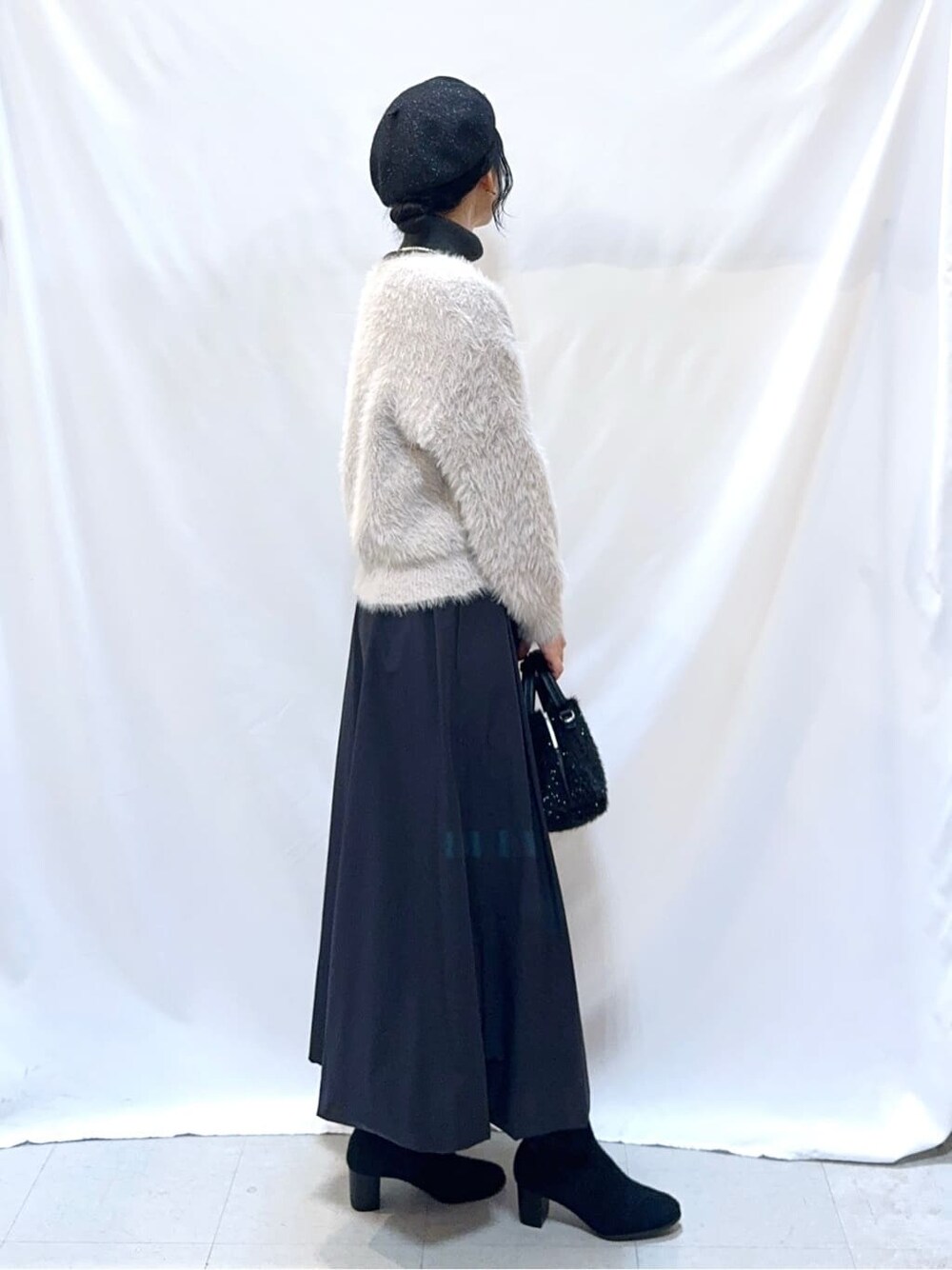グレー系のカーディガン/ボレロ、グレー系のニット/セーター、ブラック系のスカートを着用したレディースの冬コーディネートの3枚目の写真