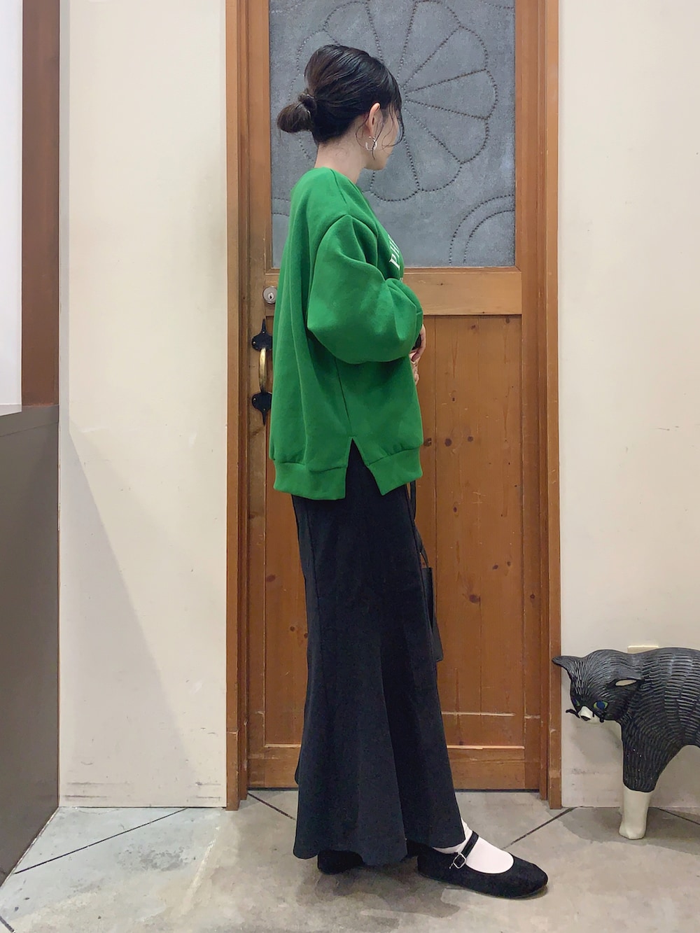 グリーン系のスウェット、ブラック系のスカート、ブラック系のショルダーバッグを着用したレディースの冬コーディネートの2枚目の写真