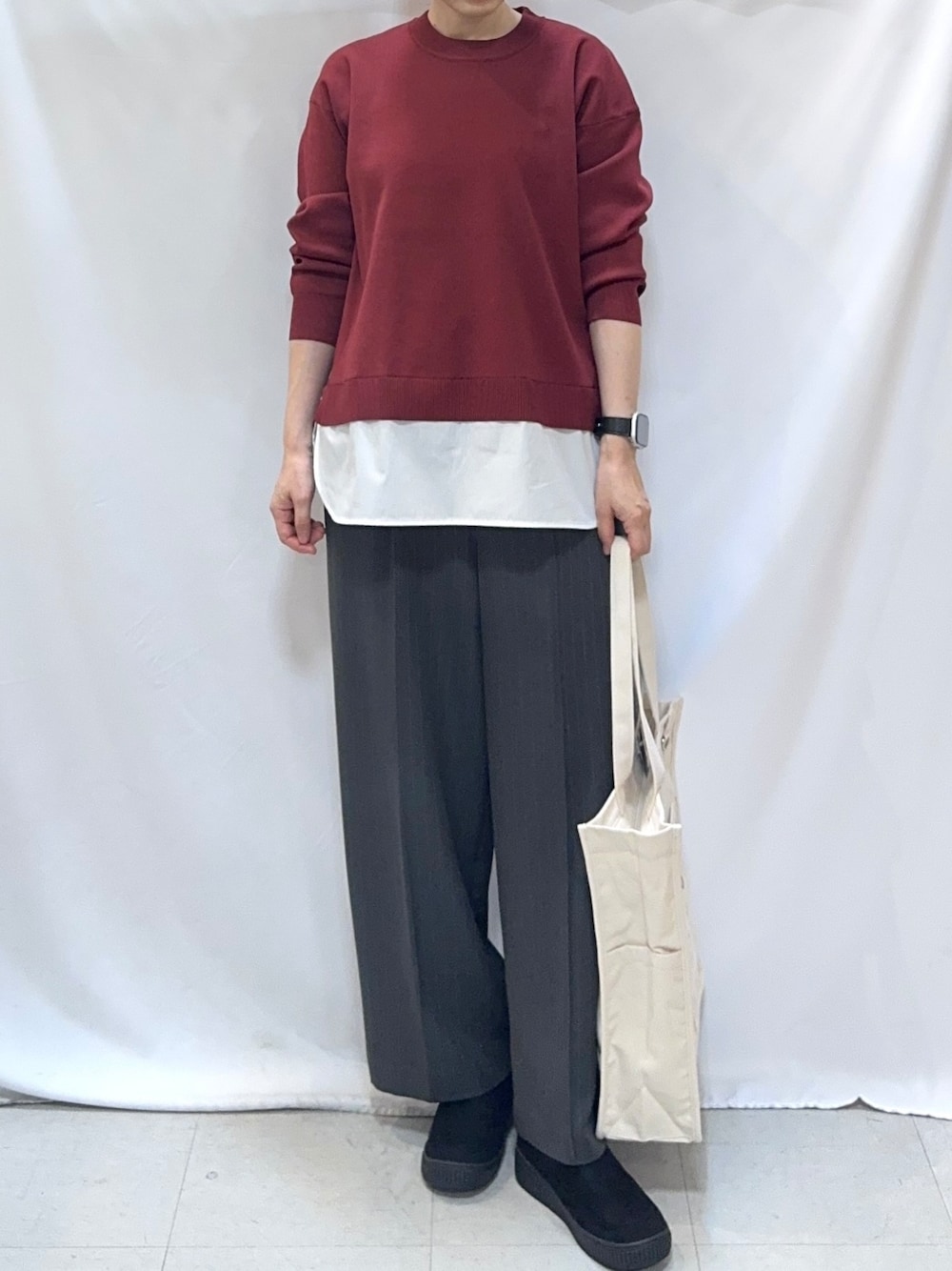 レッド系のニット/セーター、グレー系のその他パンツ、ブラック系のブーツを着用したレディースの秋コーディネートの5枚目の写真