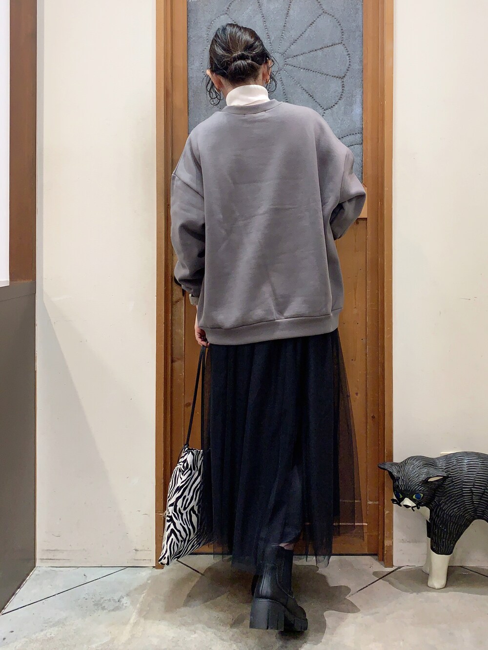 ホワイト系のニット/セーター、グレー系のスウェット、ブラック系のスカートを着用したレディースの冬コーディネートの3枚目の写真