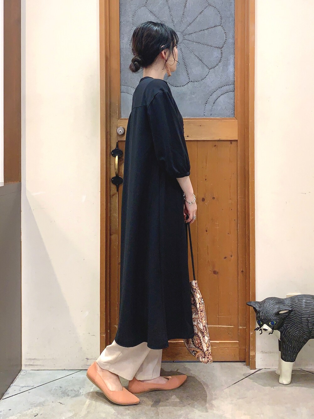 ブラック系のワンピース、ベージュ系のトートバッグ、オレンジ系のパンプスを着用したレディースの春コーディネートの3枚目の写真