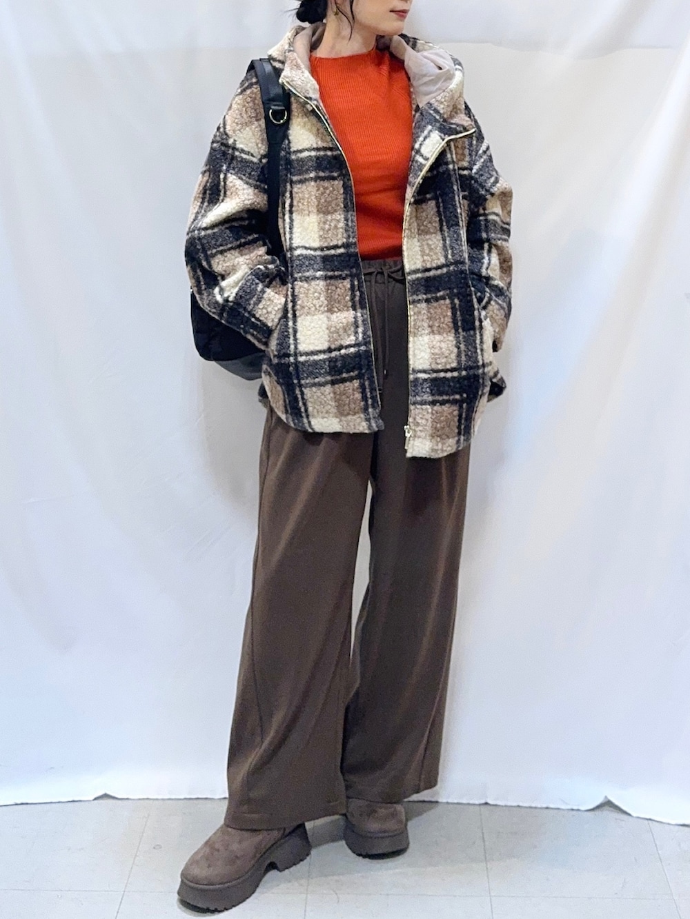 ブラウン系のその他アウター、オレンジ系のニット/セーター、ブラウン系のその他パンツを着用したレディースの秋コーディネートの4枚目の写真
