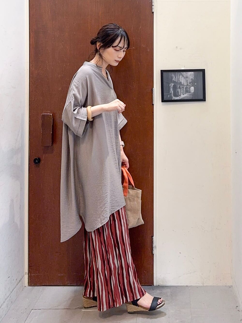 ブラウン系のチュニック、レッド系のその他パンツ、ブラック系のサンダルを着用したレディースの夏コーディネートの3枚目の写真