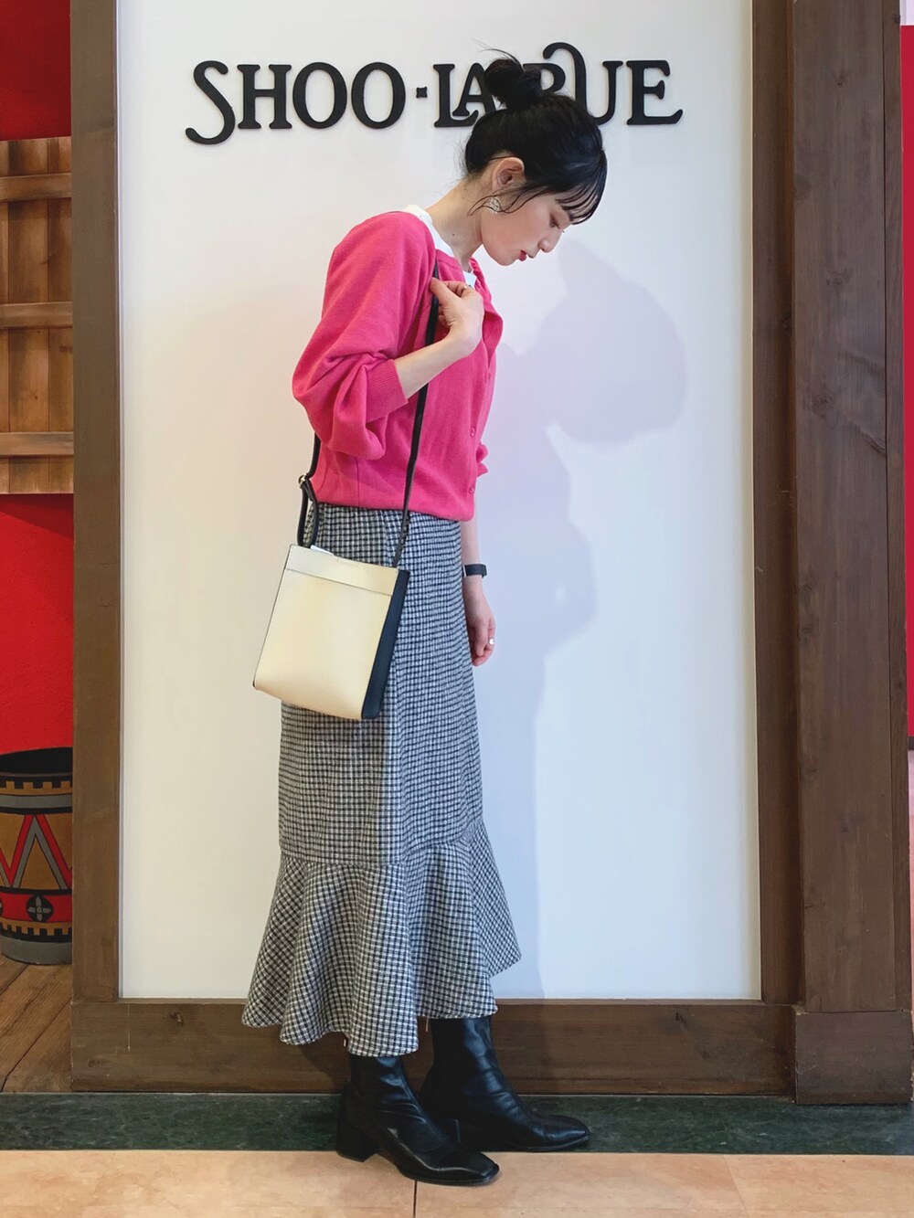 ピンク系のニット/セーター、ブラック系のスカート、ブラック系のショルダーバッグを着用したレディースの冬コーディネートの2枚目の写真