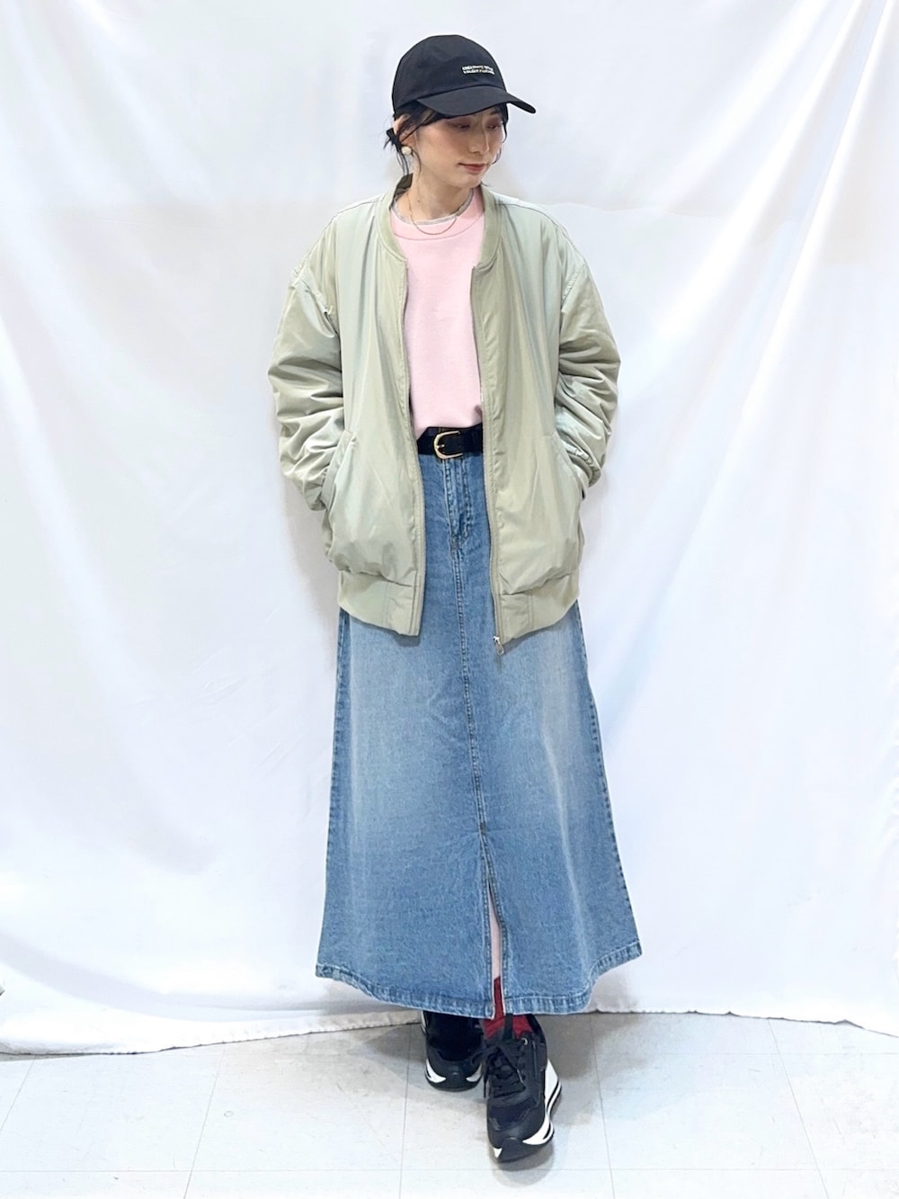 グリーン系のブルゾン、ピンク系のニット/セーター、ブルー系のデニムスカートを着用したレディースの冬コーディネートの2枚目の写真