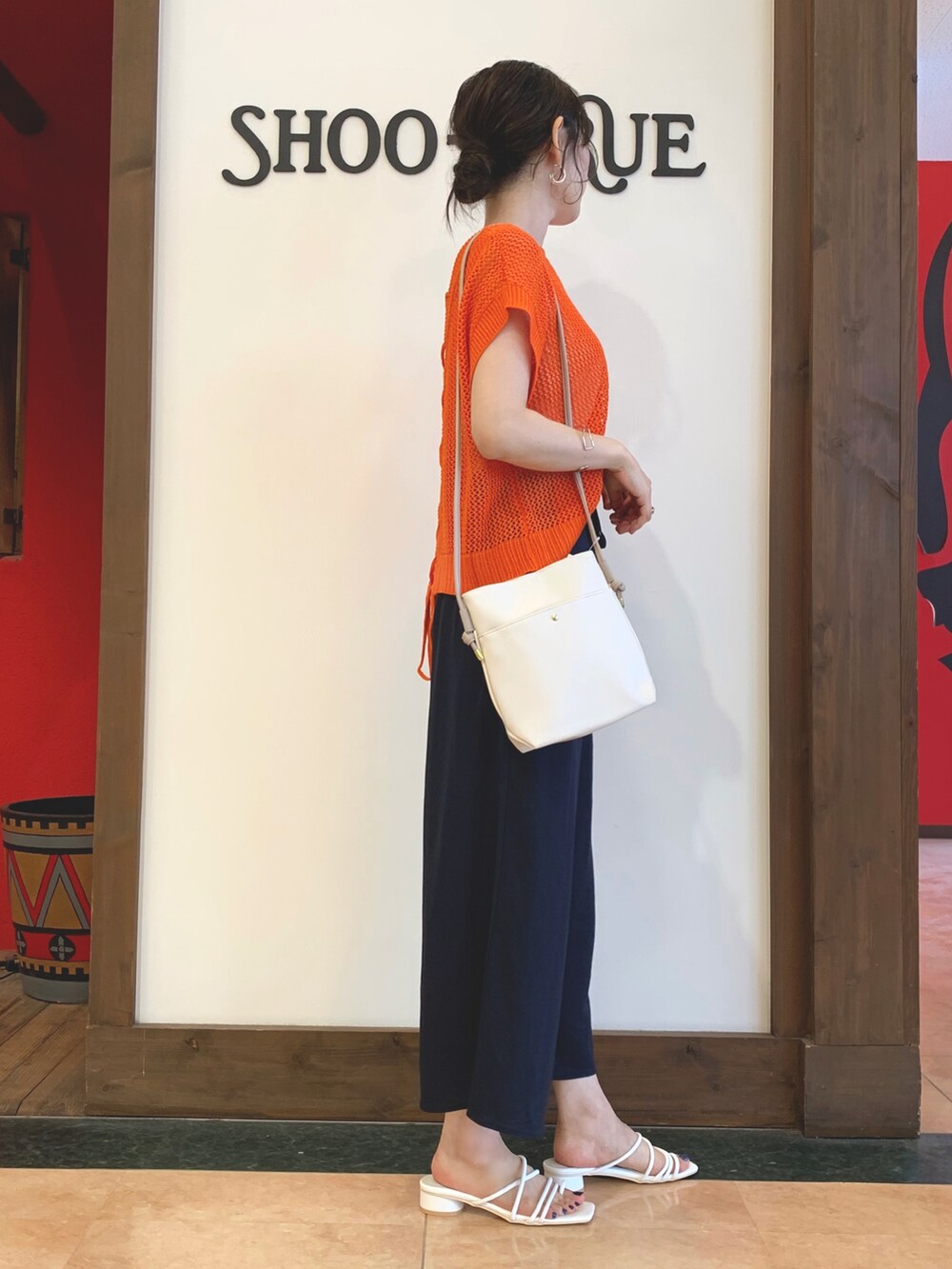 オレンジ系のニット/セーター、ブルー系のその他パンツ、ホワイト系のサンダルを着用したレディースの夏コーディネートの3枚目の写真