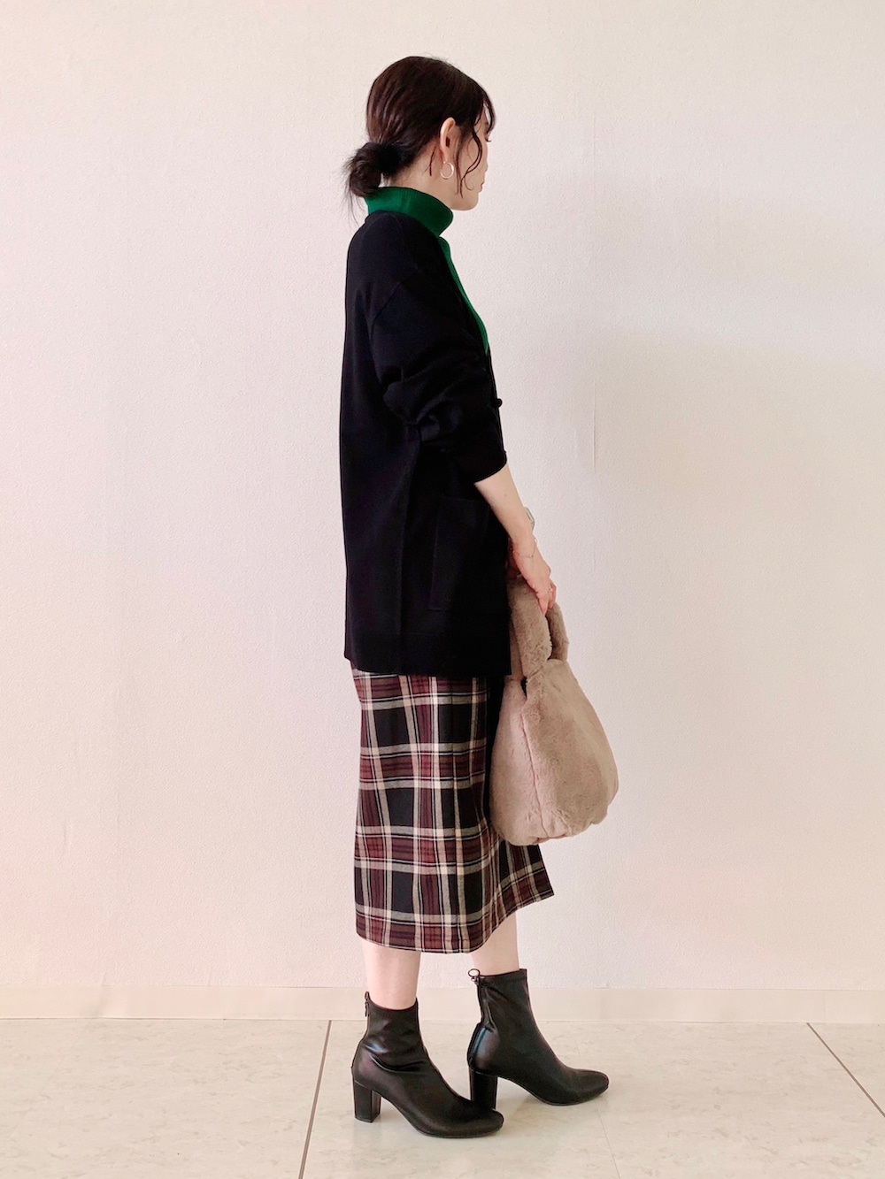 グリーン系のニット/セーター、ブラック系のカーディガン/ボレロ、ブラック系のスカートを着用したレディースの秋コーディネートの2枚目の写真