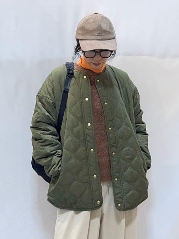 グリーン系のブルゾン、ブラウン系のニット/セーター、オレンジ系のTシャツ/カットソーを着用したレディースの秋コーディネートの6枚目の写真
