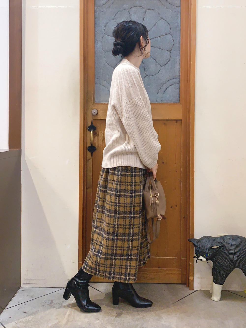 ベージュ系のニット/セーター、イエロー系のスカート、グレー系のショルダーバッグを着用したレディースの冬コーディネートの3枚目の写真