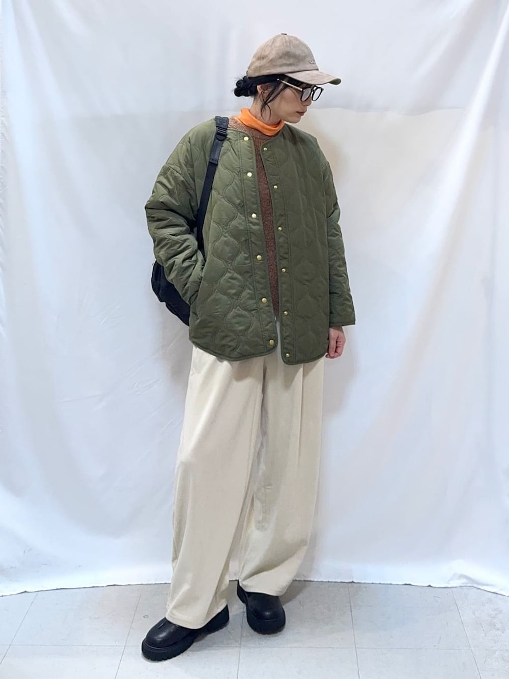 グリーン系のブルゾン、ブラウン系のニット/セーター、オレンジ系のTシャツ/カットソーを着用したレディースの秋コーディネートの2枚目の写真