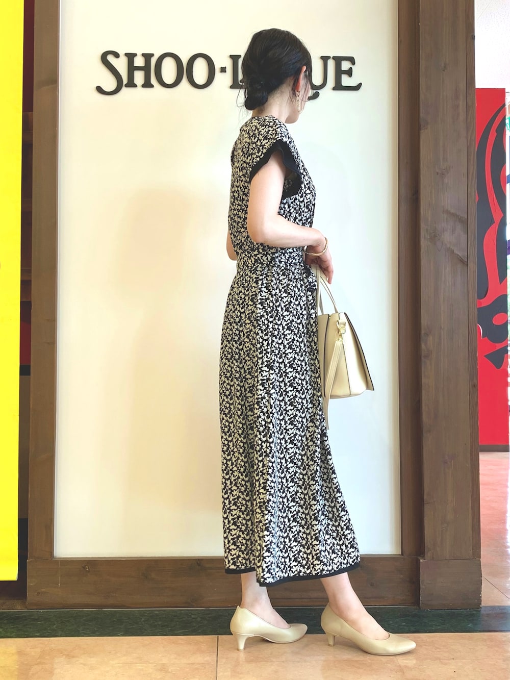 ブラック系のワンピース、ホワイト系のトートバッグ、ベージュ系のパンプスを着用したレディースの夏コーディネートの2枚目の写真