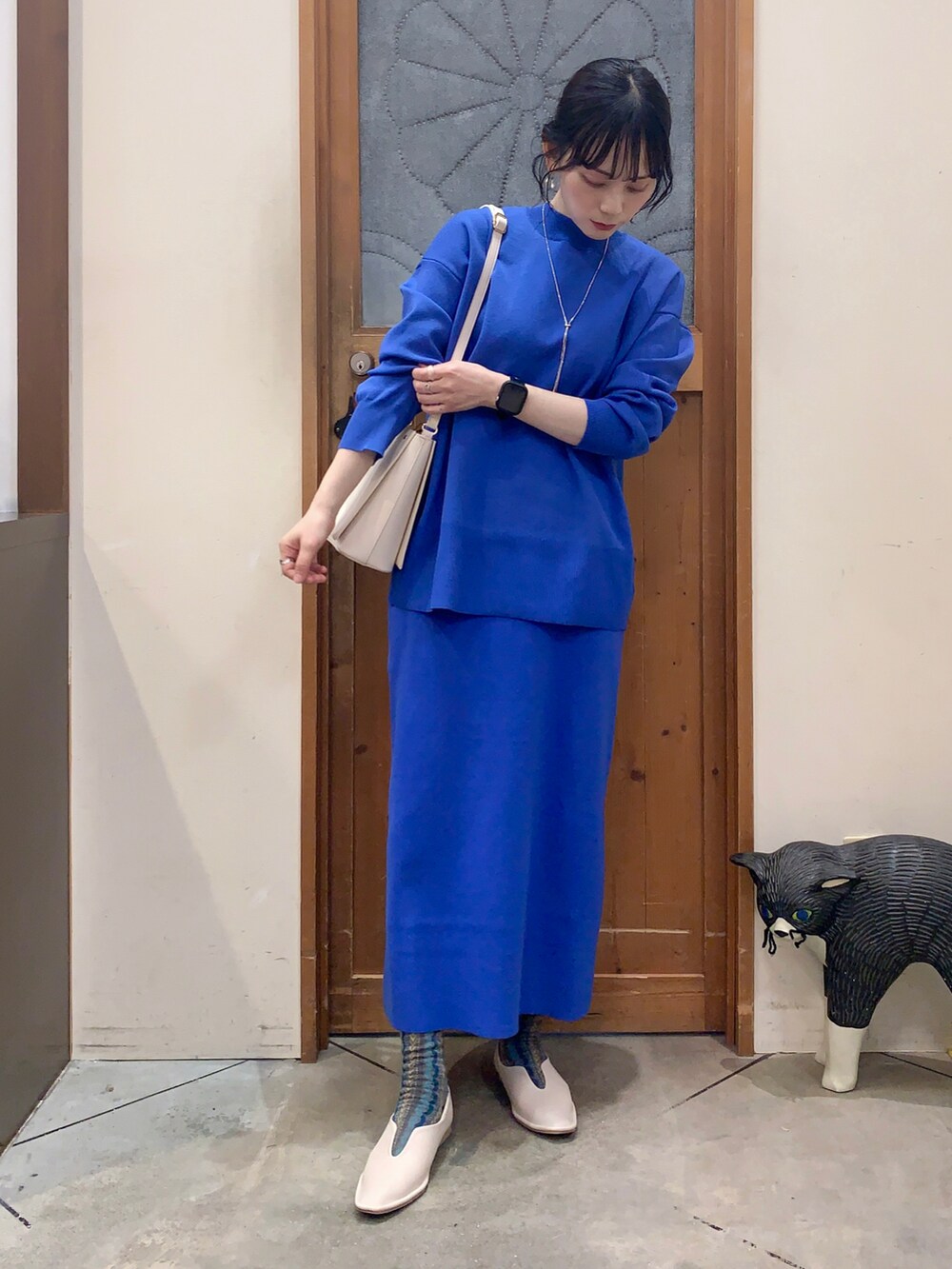 ブルー系のニット/セーター、ブルー系のスカート、ホワイト系のパンプスを着用したレディースの冬コーディネートの2枚目の写真