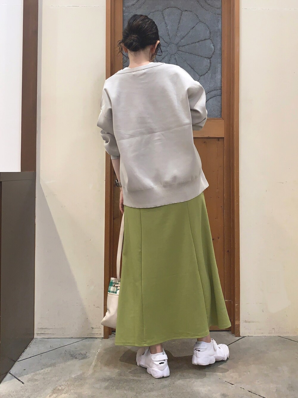 ホワイト系のTシャツ/カットソー、ベージュ系のカーディガン/ボレロ、グリーン系のスカートを着用したレディースの秋コーディネートの3枚目の写真