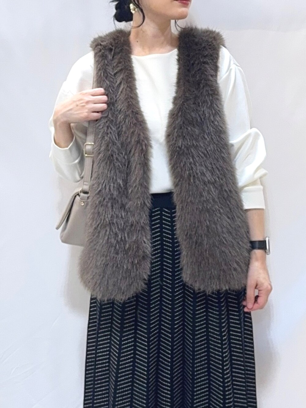 ブラウン系のベスト、ホワイト系のTシャツ/カットソー、ブラック系のスカートを着用したレディースの秋コーディネートの4枚目の写真