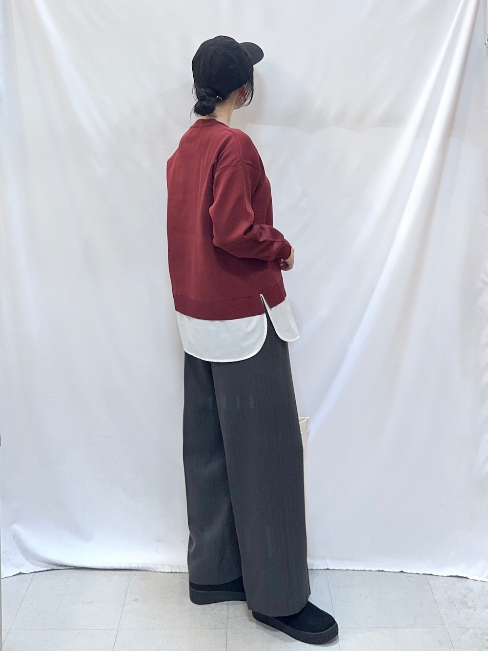 レッド系のニット/セーター、グレー系のその他パンツ、ブラック系のブーツを着用したレディースの秋コーディネートの2枚目の写真