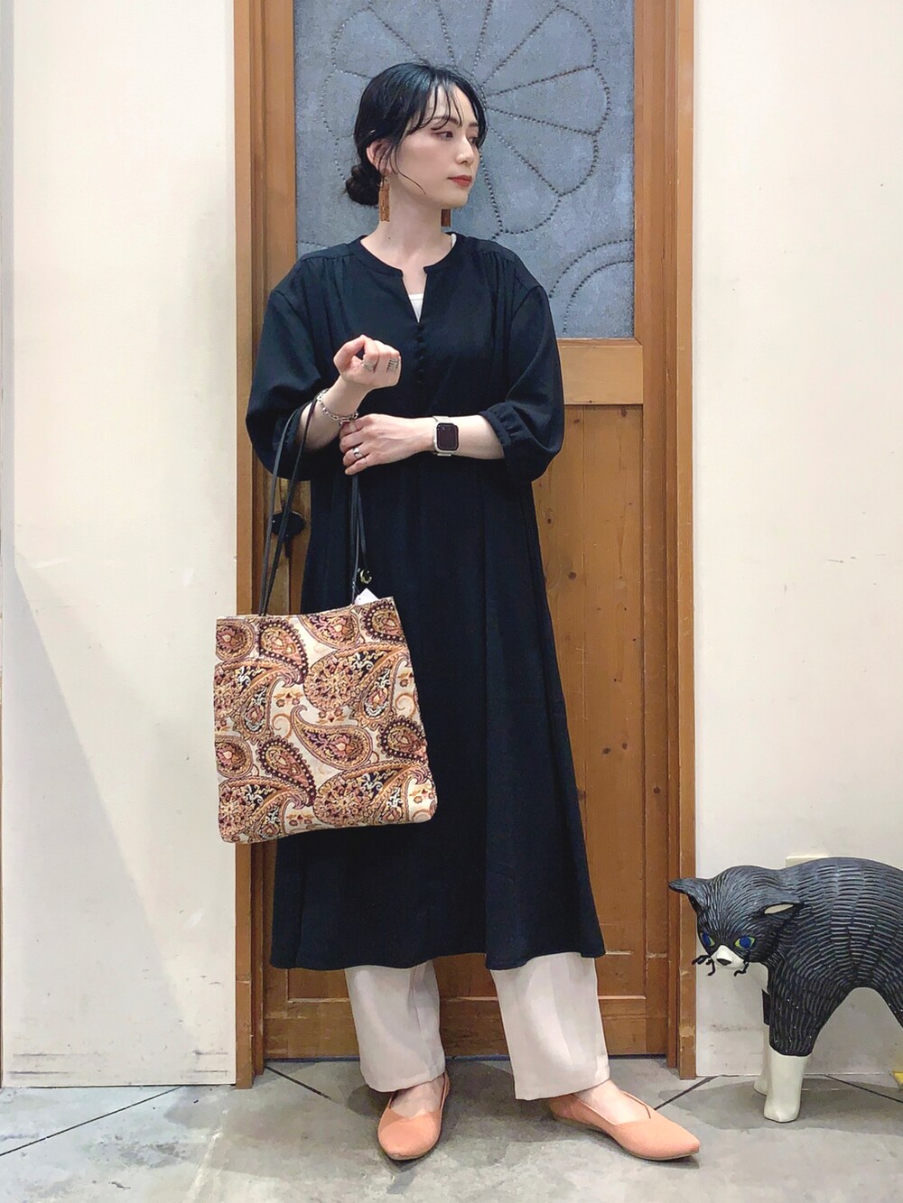 ブラック系のワンピース、ベージュ系のトートバッグ、オレンジ系のパンプスを着用したレディースの春コーディネートの2枚目の写真