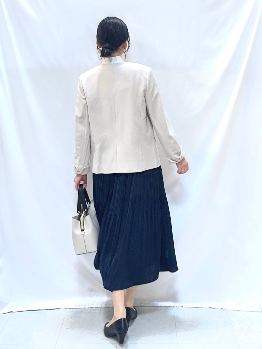 ベージュ系のノーカラージャケット、ホワイト系のシャツ/ブラウス、ブルー系のスカートを着用したレディースの冬コーディネートの3枚目の写真