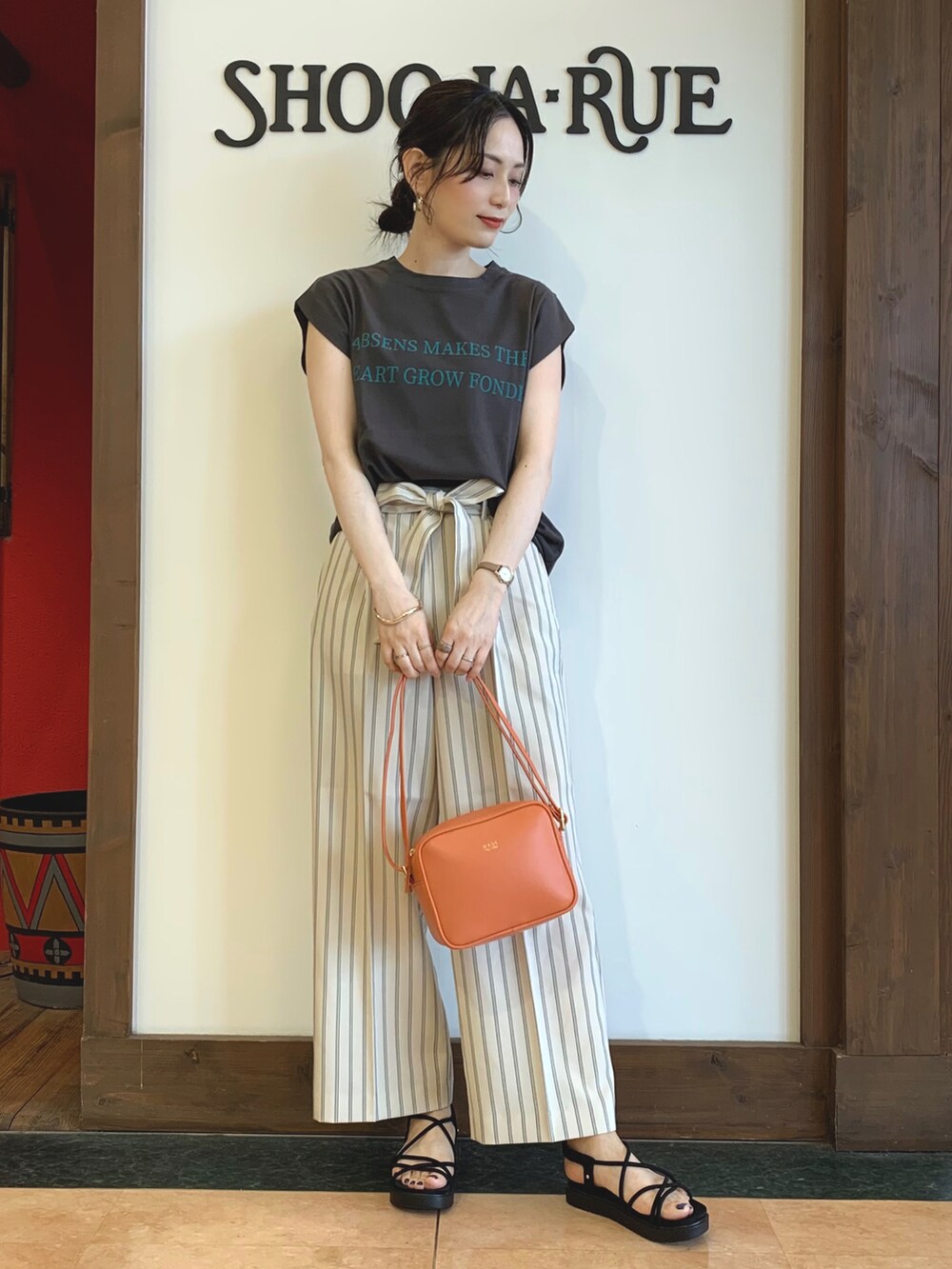 グレー系のTシャツ/カットソー、ベージュ系のその他パンツ、オレンジ系のショルダーバッグを着用したレディースの夏コーディネートの2枚目の写真