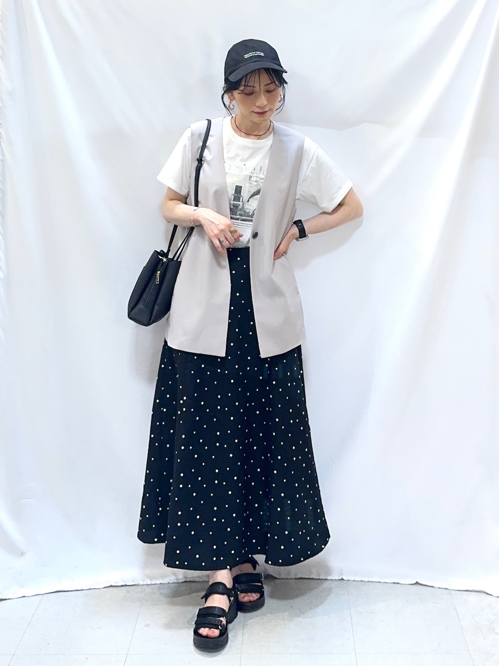 ベージュ系のベスト、ホワイト系のTシャツ/カットソー、ブラック系のスカートを着用したレディースの夏コーディネートの3枚目の写真